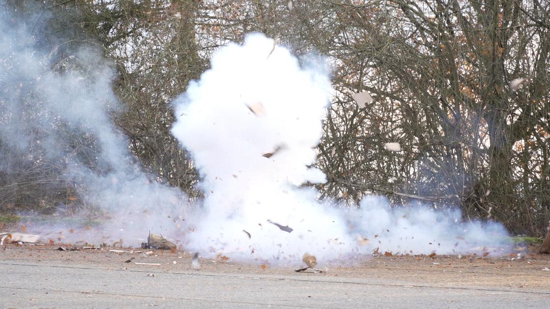Explodierende Böller. Fetzen fliegen durch die Luft, viel Qualm steigt auf.