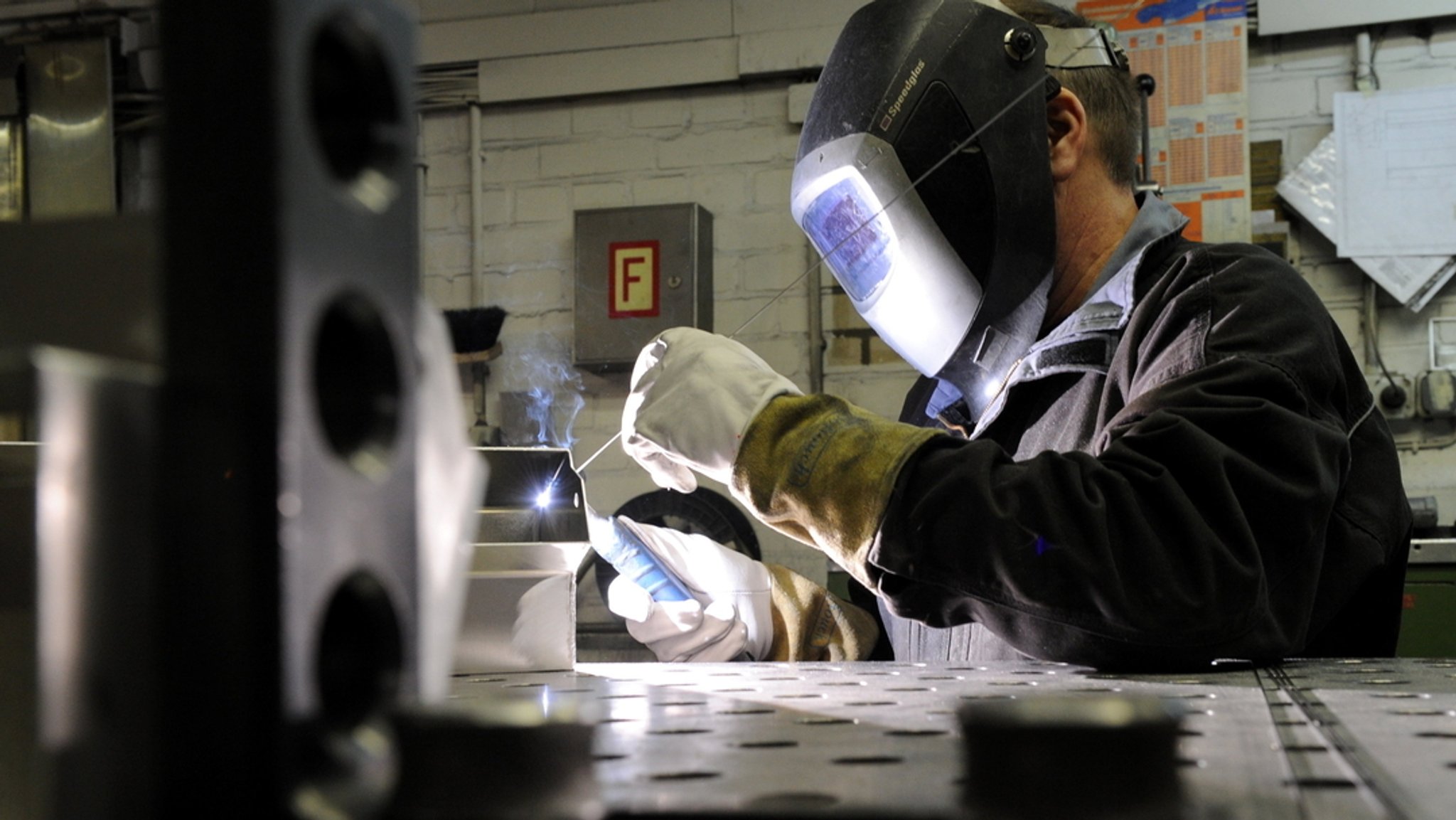 Ein Mitarbeiter eines metallverarbeitenden Betriebes schweißt eine Naht an einem Werkstück.