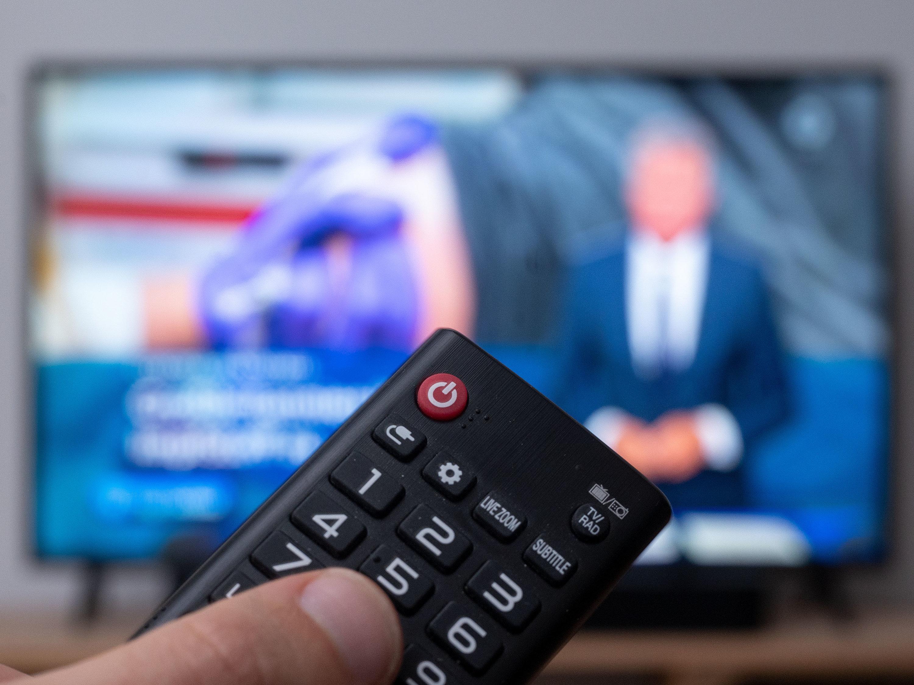 Eine Fernbedienung mit Fernseher im Hintergrund