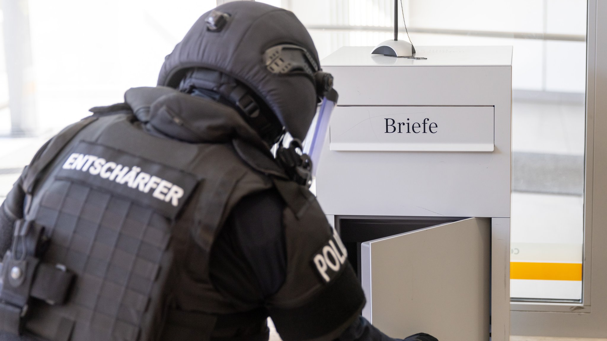 Polizist eines Räumkommandos öffnet einen Briefkasten