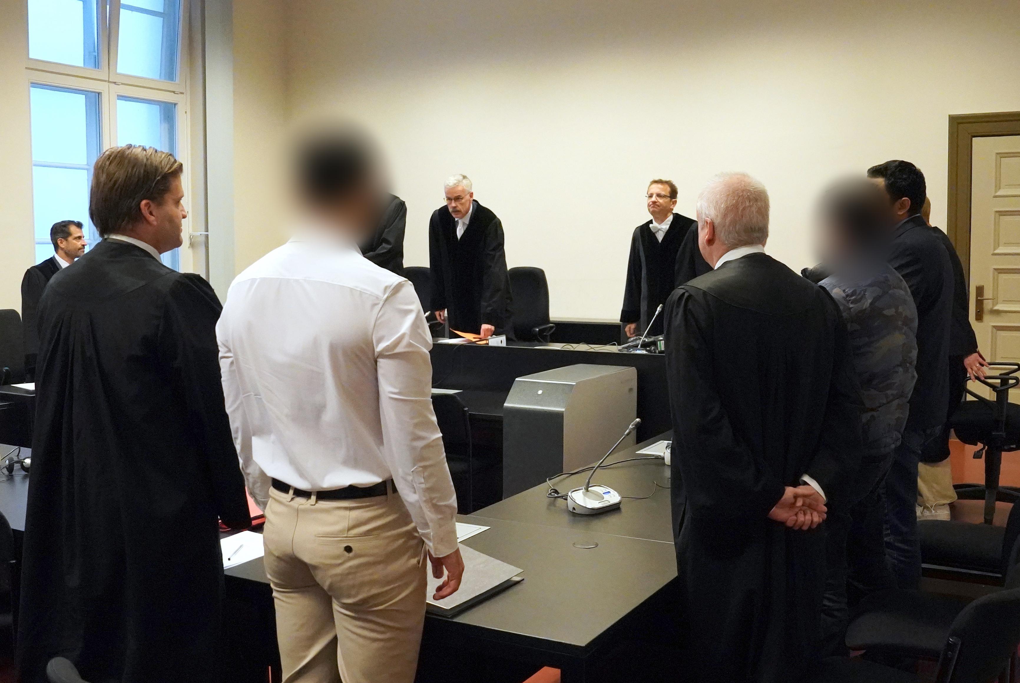 Die angeklagten syrischen Brüder (vorne 2.v.l und 2.v.r) stehen zu Beginn des Prozesses im Sitzungssaal
