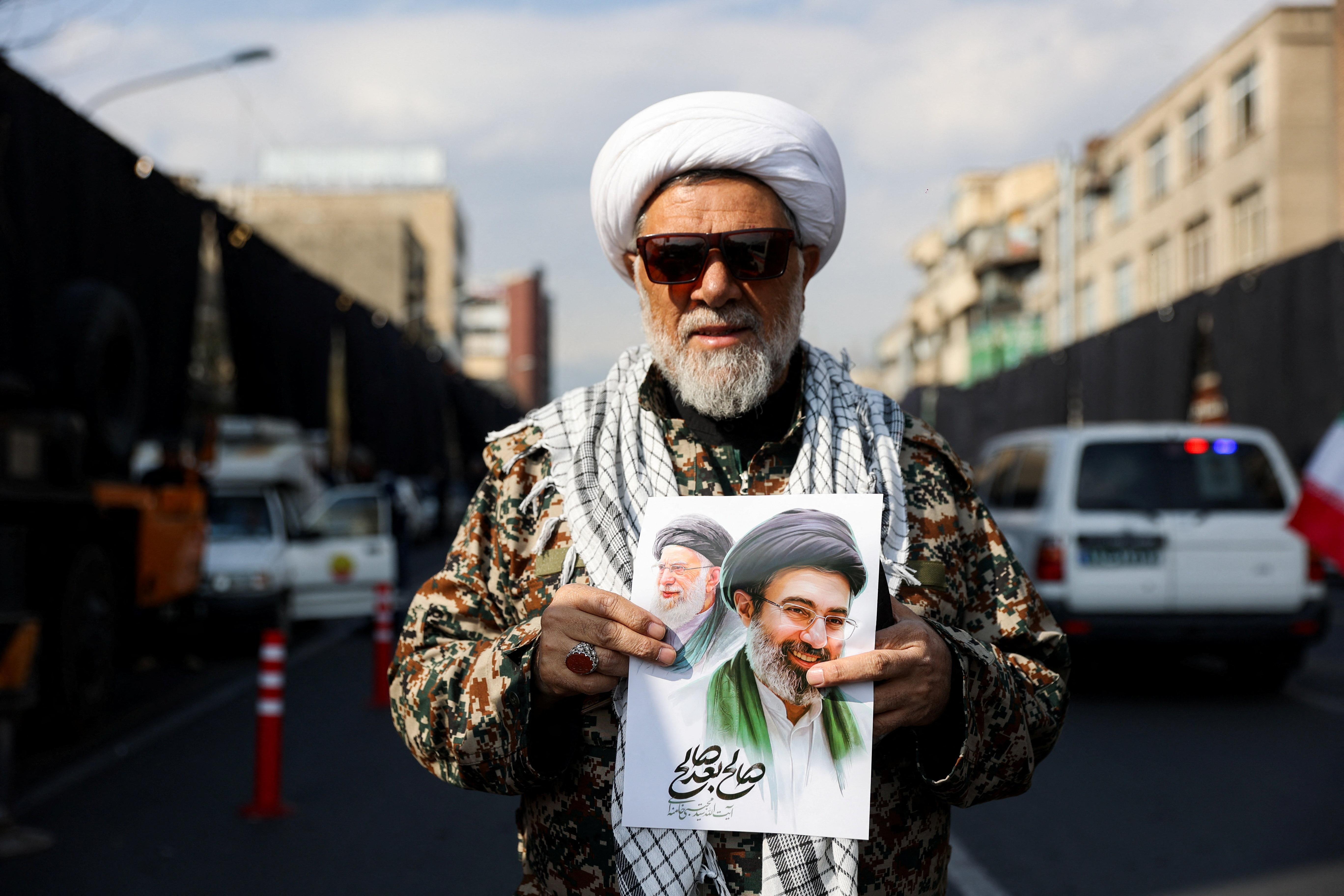 Ein Mann hält ein Bild von Modschtaba Chamenei und den getöteten Ajatollah Ali Chamenei 