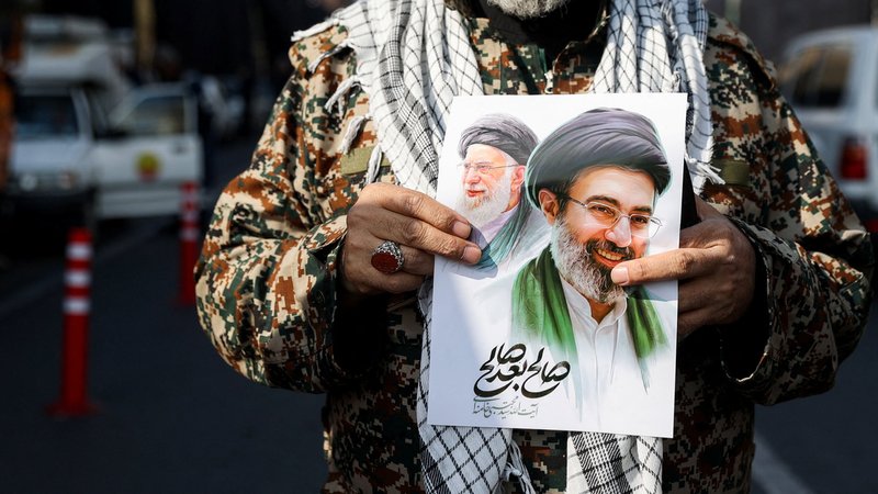 Ein Mann hält ein Bild von Modschtaba Chamenei und den getöteten Ajatollah Ali Chamenei | Bild: Majid Asgaripour/WANA (West Asia News Agency) via REUTERS Ein Mann hält ein Bild von Modschtaba Chamenei und den getöteten Ajatollah Ali Chamenei