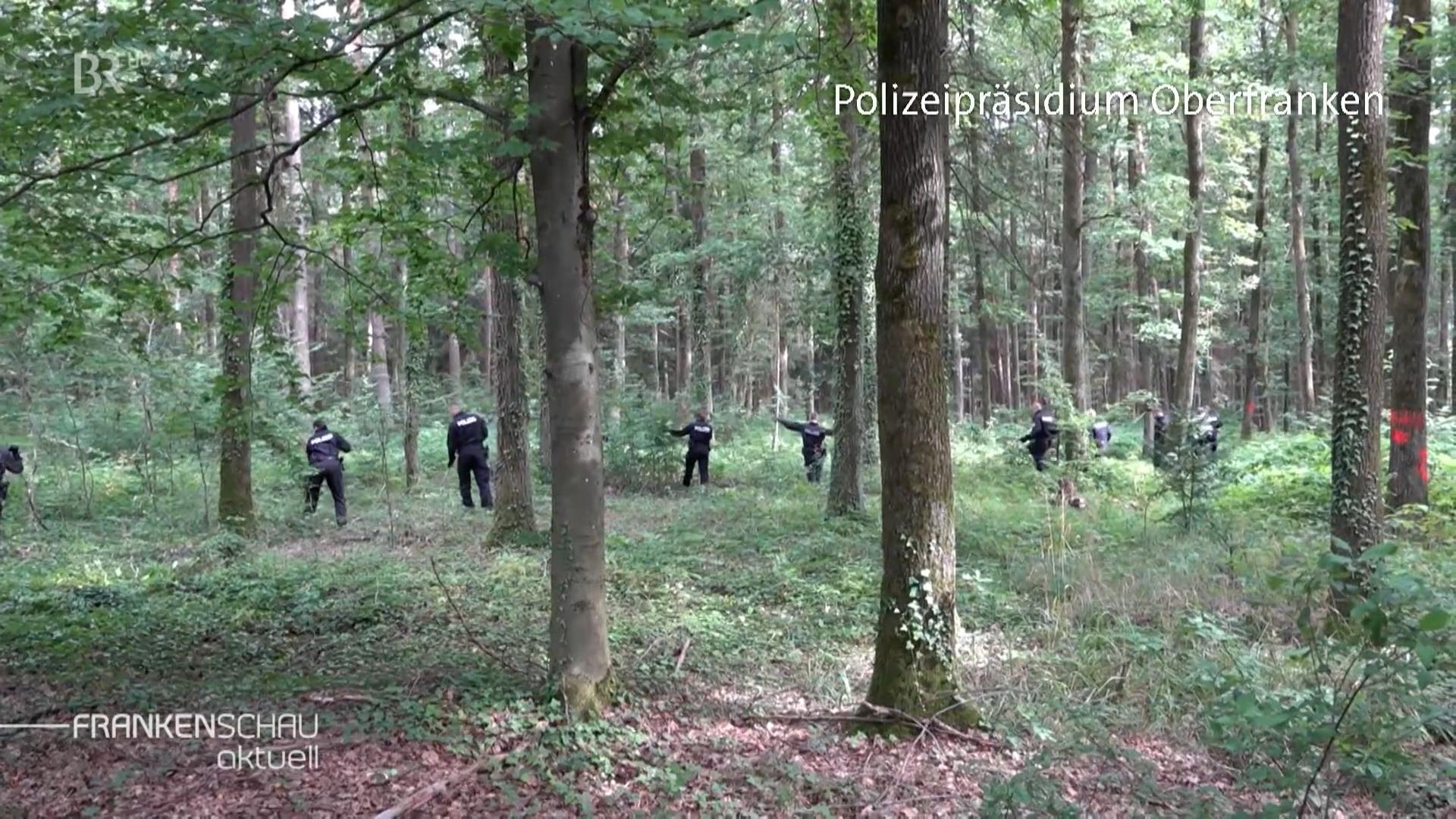 Polizeibeamte durchsuchen einen Wald in Oberfranken