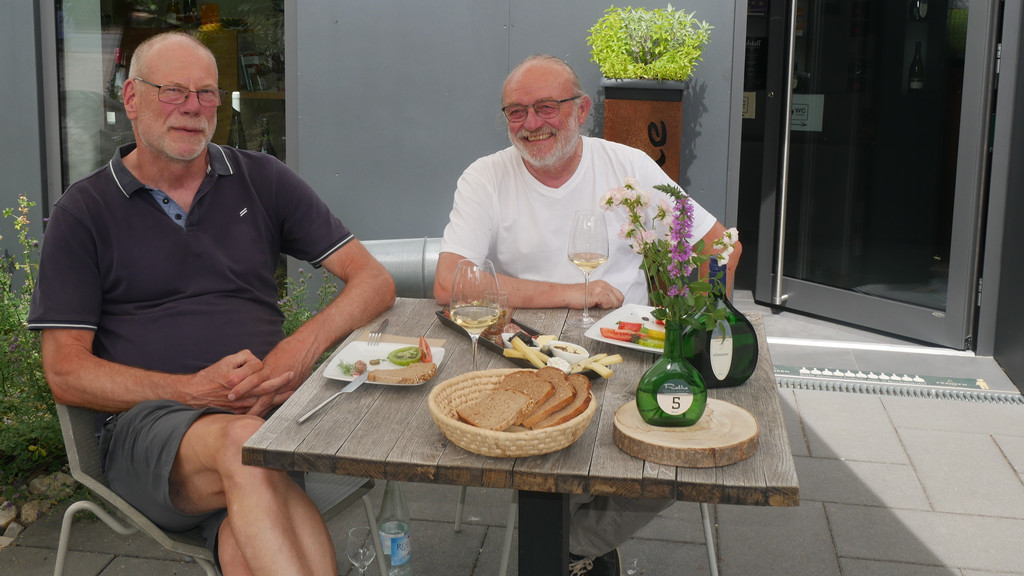 Gerd Sych und Manfred Rothe sitzen am gedeckten Tisch des Weinbistros.