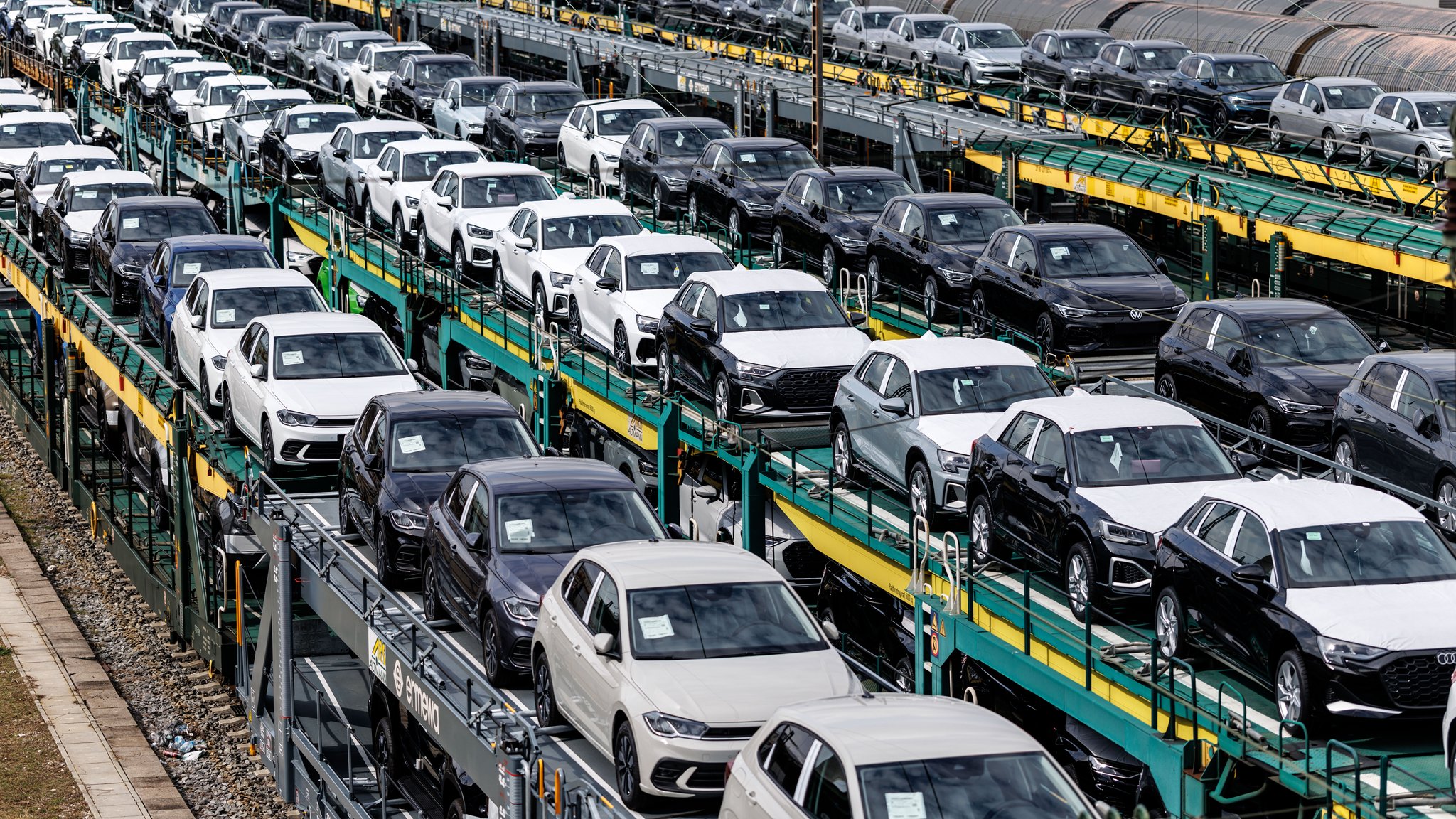 Zahlreiche Autotransportwagen mit Neufahrzeugen der Unternehmen Audi und Volkswagen stehen am 25.03.2025 auf den Gleisanlagen von einem Rangierbahnhof in München (Bayern). 