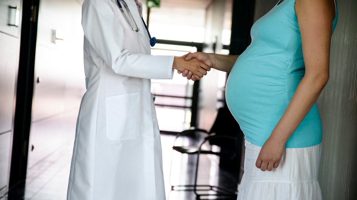 Eine Ärztin schüttelt einer Schwangeren die Hand.