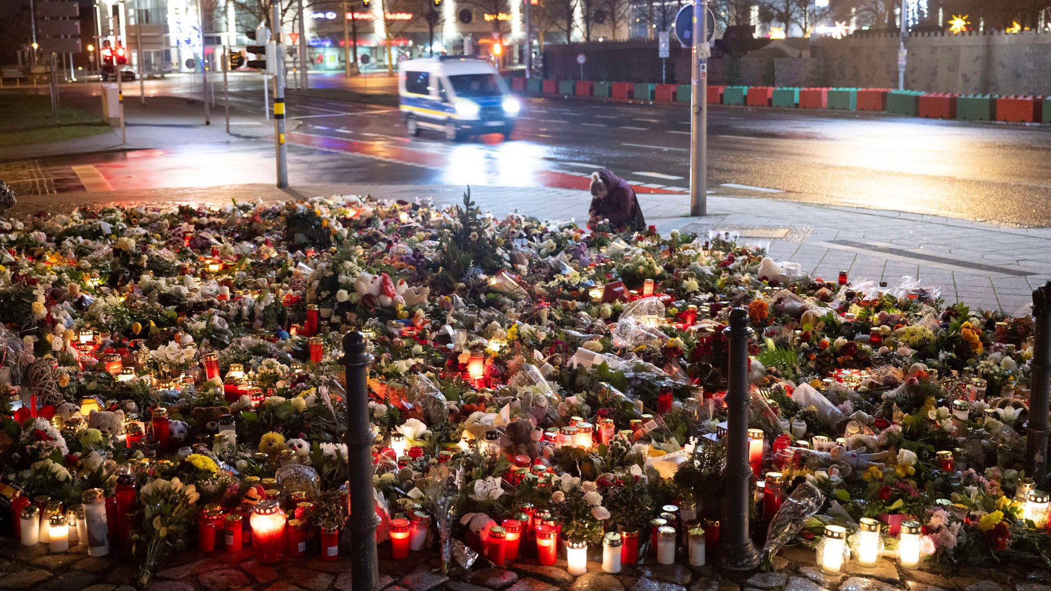 Zahlreiche Kerzen, Blumen und Kränze liegen beziehungsweise stehen vor dem Eingang der Johanniskirche.