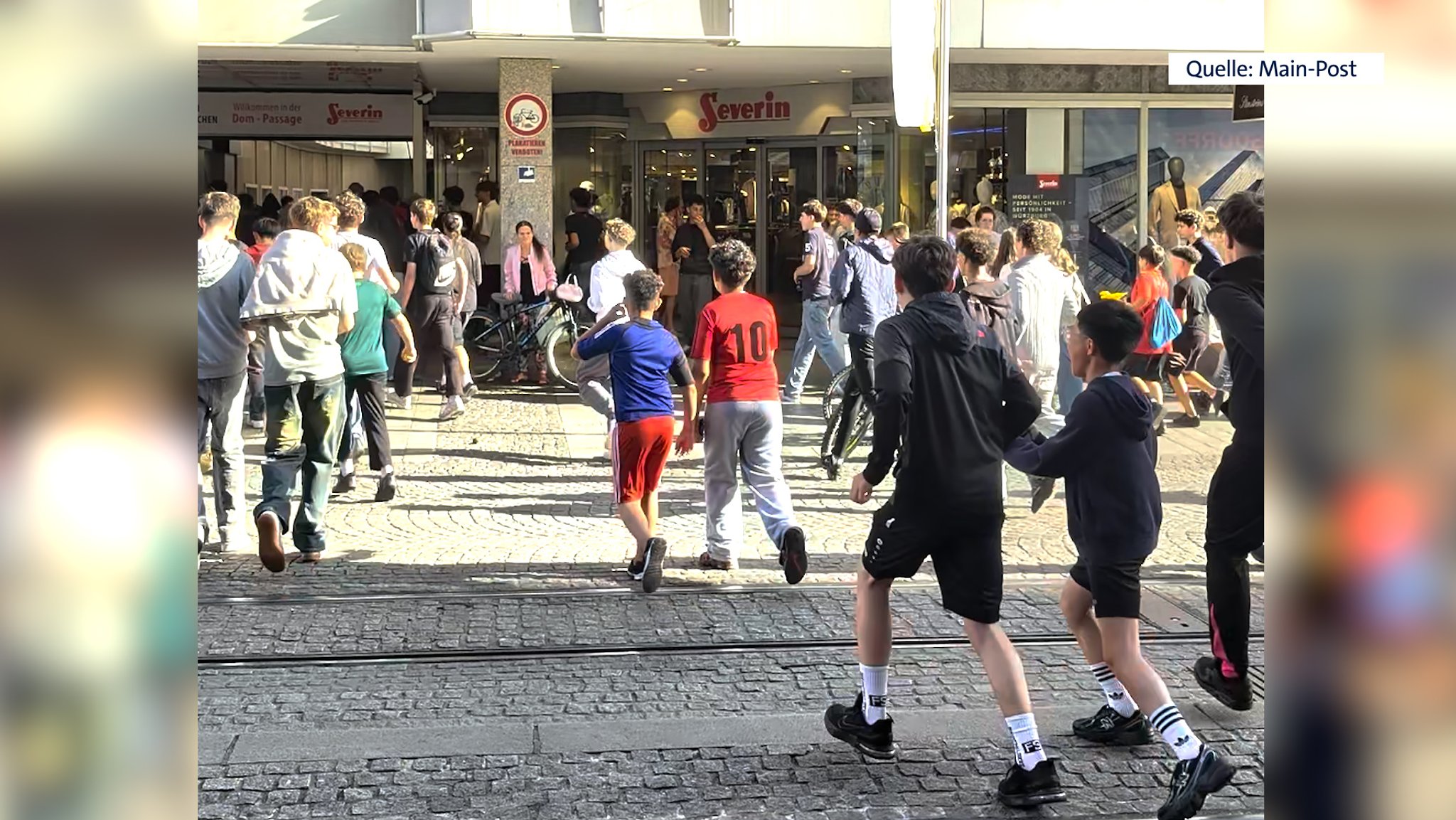 Eine Gruppe von Jugendlichen rennt auf einen Laden in Würzburg zu.