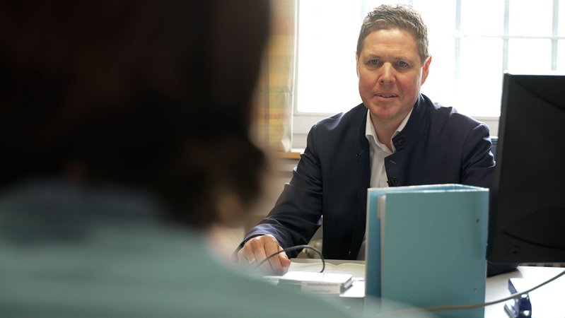 Anstaltsbeirat Joachim Konrad sitzt im Sprechraum der JVA Kempten und spricht mit einem Gefangenen. | Bild: BR / Michael Frick Anstaltsbeirat Joachim Konrad sitzt im Sprechraum der JVA Kempten und spricht mit einem Gefangenen.