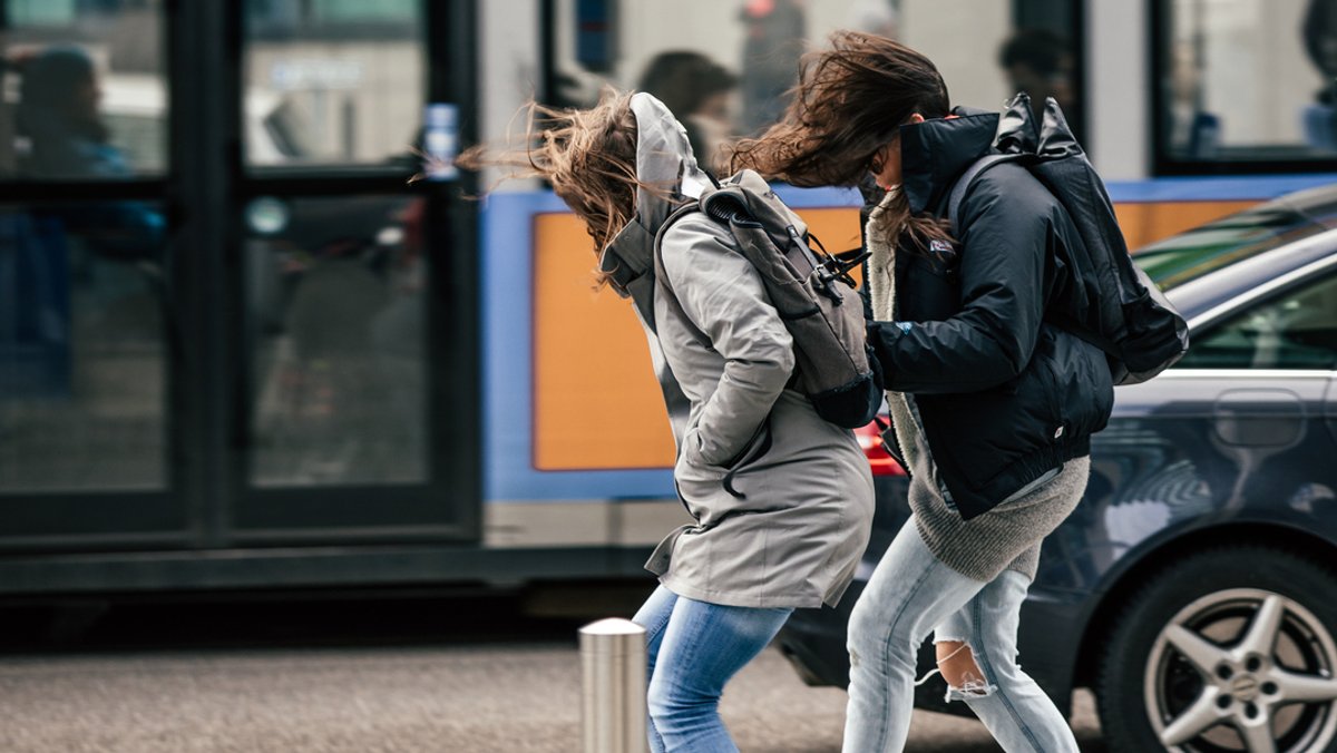 Archivbild: Zwei Fußgängerinnen in München kämpfen gegen starke Windböen an.