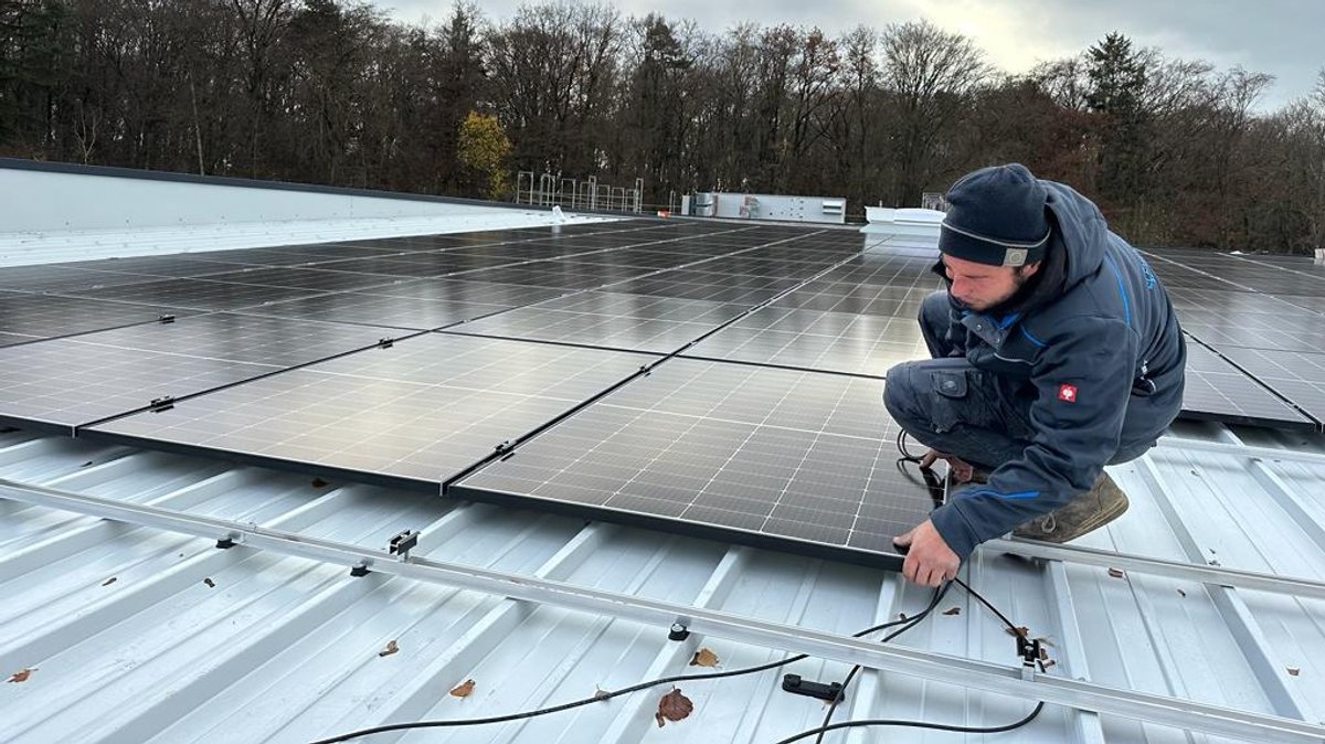 Arbeiter, der auf dem Dach eine PV-Anlage montiert. 