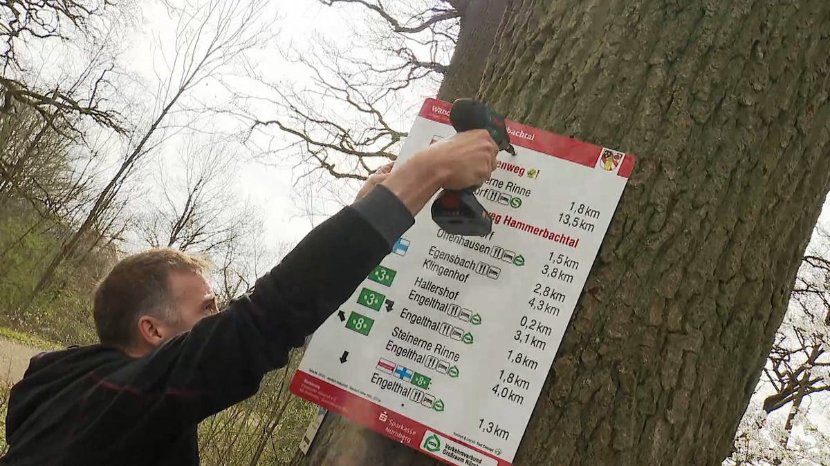 Ein Mitgleid des Fränkischen Albvereins montiert das letzte der 90 Schilder, die zukünftig Wanderer durchs Hammerbachtal leiten sollen.