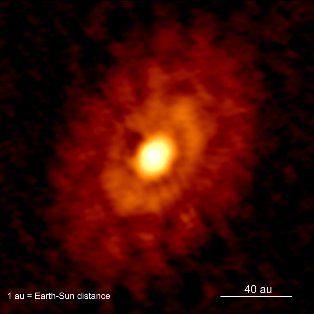 Der Bildausschnitt zeigt eine astronomische Aufnahme des jungen Sternsystems IRS 63, in dem ein junger Protostern von ringförmigen Strukturen aus Gas und Staub umgeben ist.