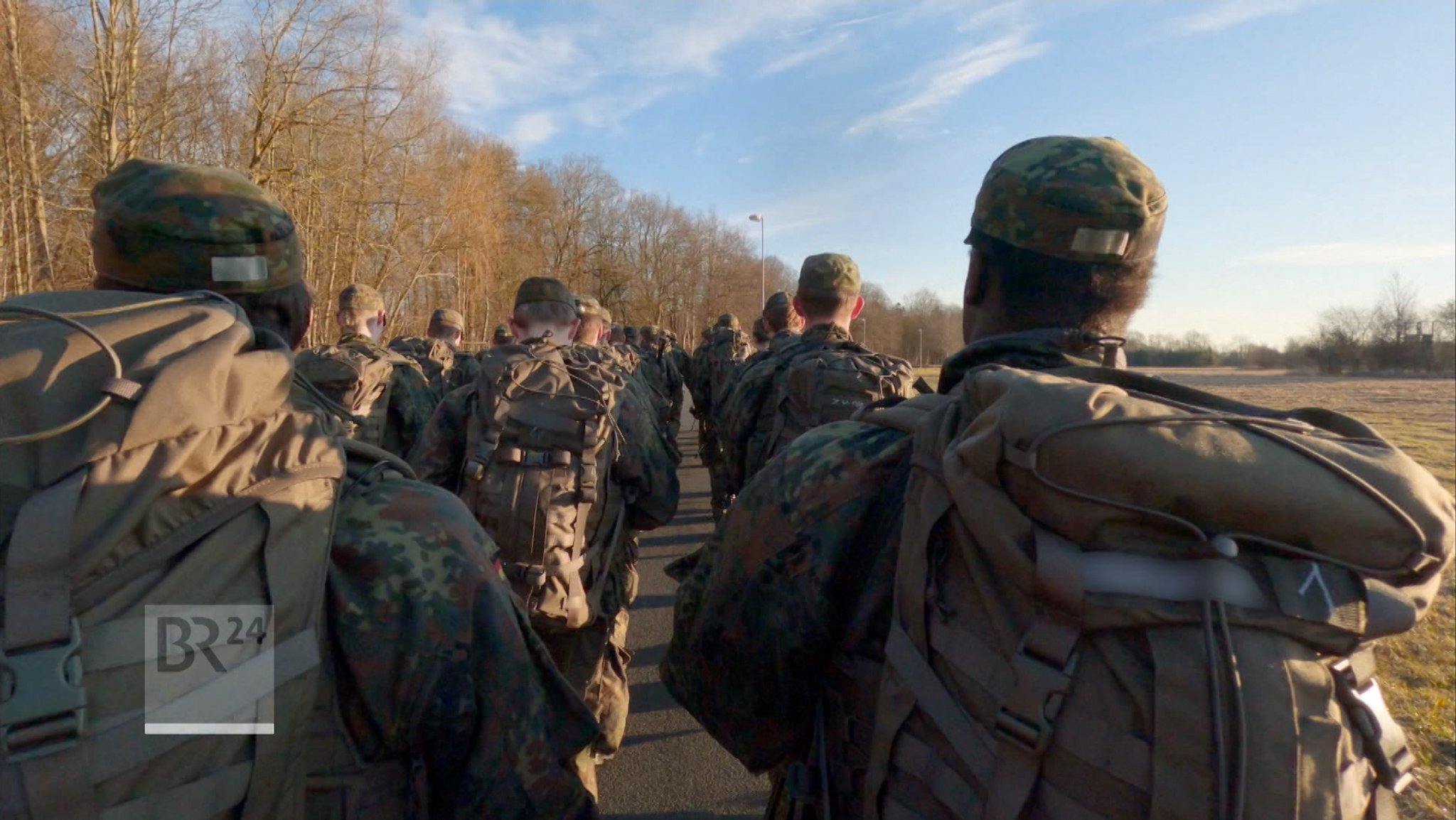 Soldaten marschieren mit Rucksäcken auf einem Feldweg