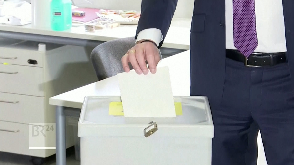Ein Mann steckt den Wahlumschlag in die Urne