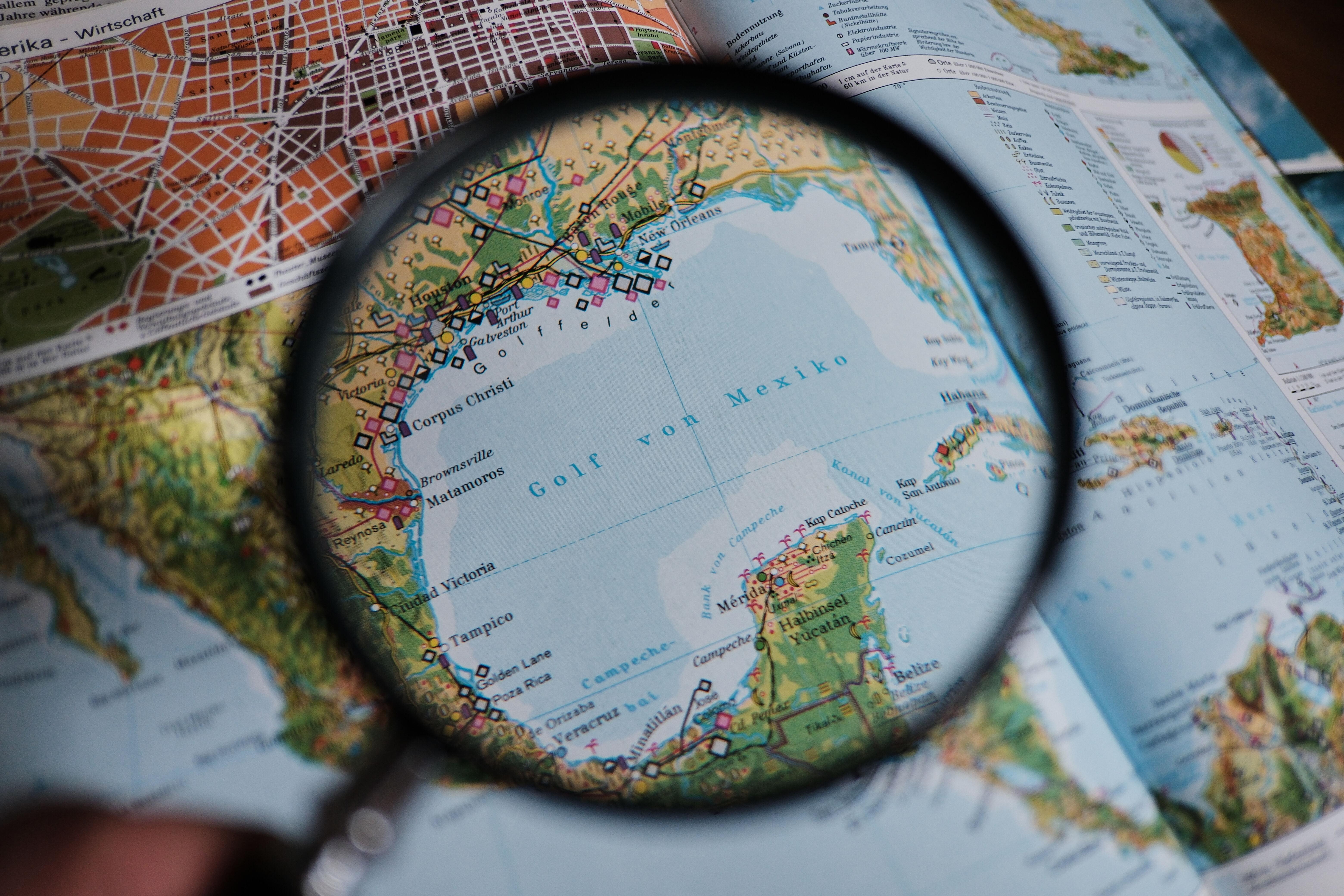 Eine Lupe wird in einem Atlas über den Golf von Mexiko gehalten (Illustration). 