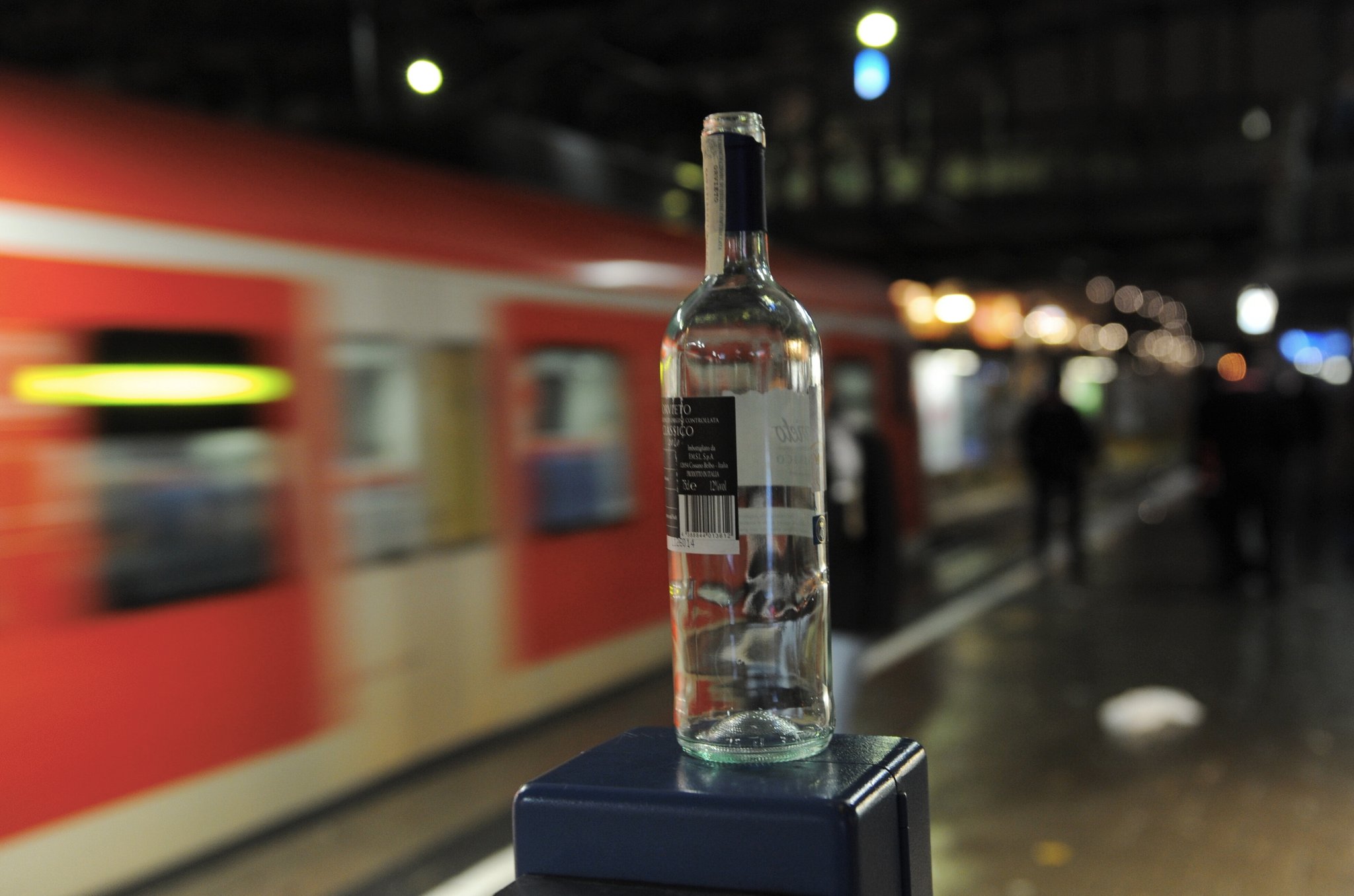 Eine leere Weinflasche steht an einem Bahnsteig in München auf einem Fahrkarten-Entwerter (Archivbild)