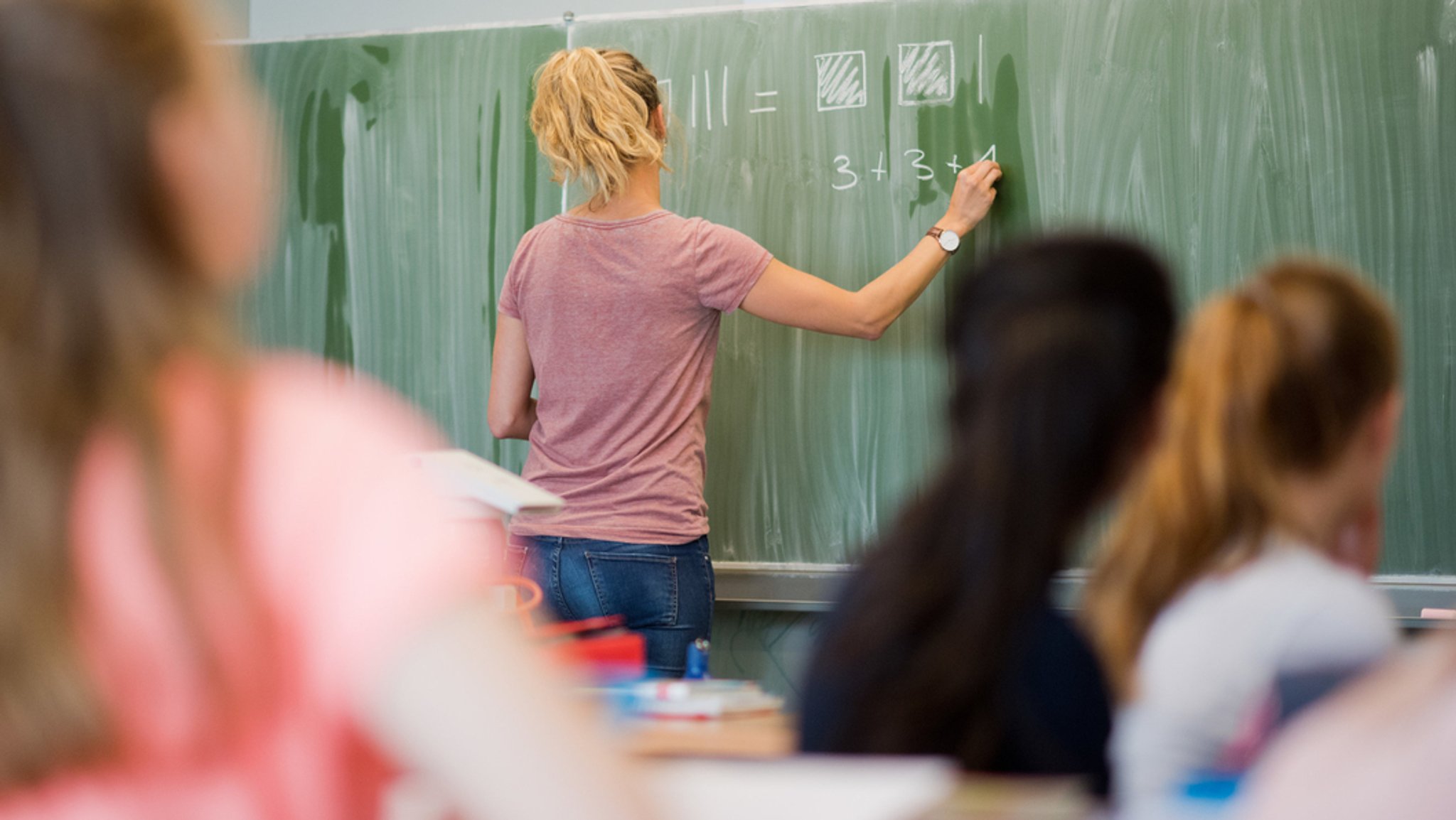  Eine Lehrerin schreibt im Mathematikunterricht an eine Schultafel.