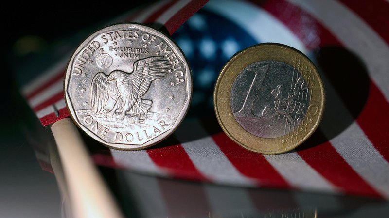 Eine US-Dollar-Münze und eine Euro-Münze liegen auf einer US-Flagge nebeneinander. | Bild: dpa/pa/Rene Traut Eine US-Dollar-Münze und eine Euro-Münze liegen auf einer US-Flagge nebeneinander.