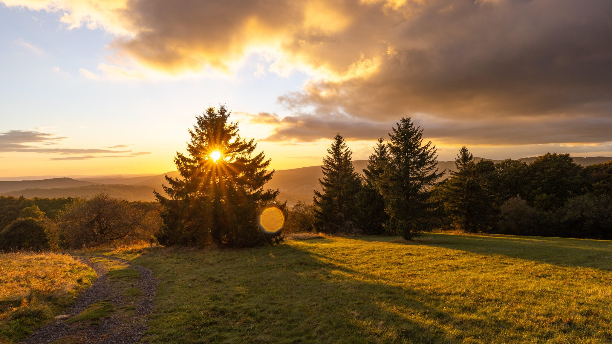 Die Abendsonne scheint auf die Landschaft am Kreuzberg in der Rhön. 