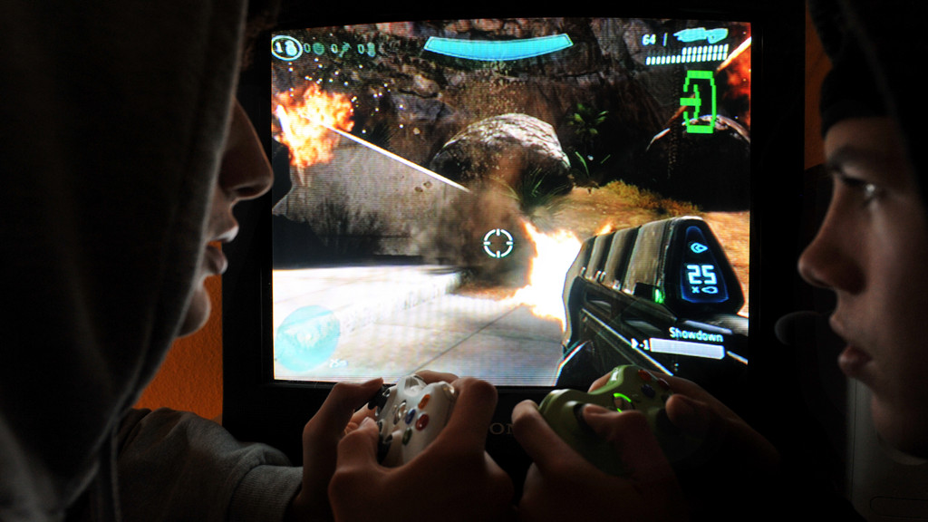 Zwei junge Männer spielen in einem abgedunkelten Raum Halo 3 aus dem Jahr 2009