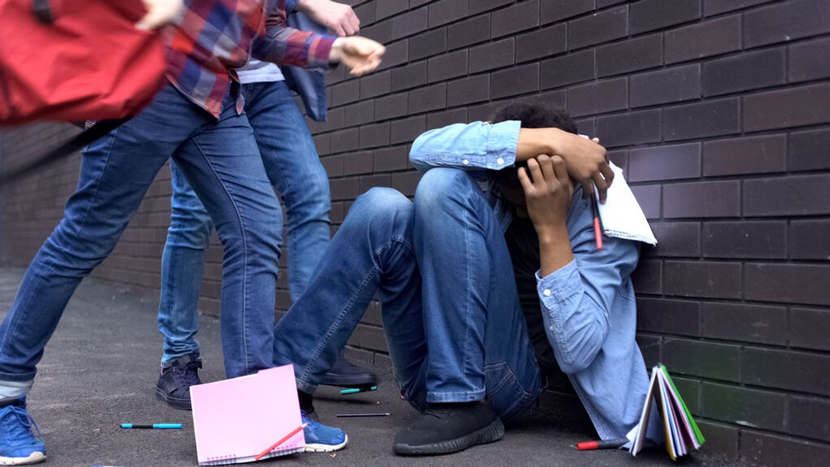 Ein afroamerikanischer Junge wird an der Schule von seinen Mitschülern gemobbt und mit Schulbüchern beworfen. 