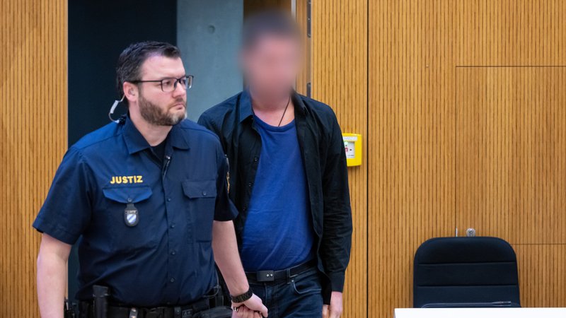 Einer von zwei wegen Mordes angeklagten Männern (r) wird am 6. März vor Beginn der Verhandlung in den Hochsicherheitsgerichtssaal vom Landgericht München II geführt.