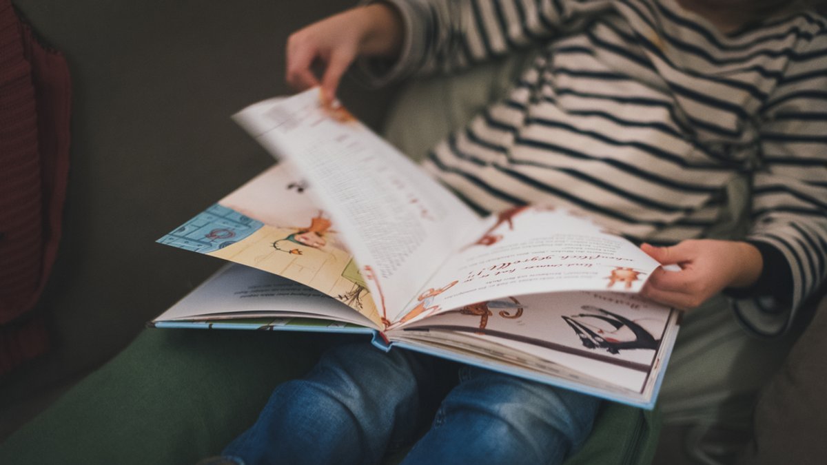 Ein Kind liest in einem Bilderbuch.