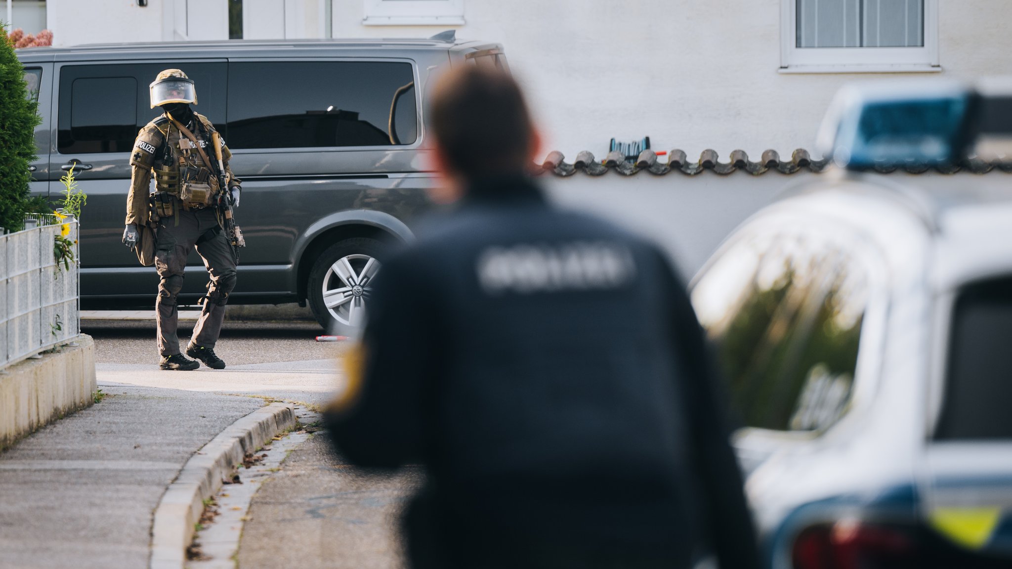 Hinter einem Polizisten in Unschärfe sieht man einen weiteren Beamten in Tarnkleidung.