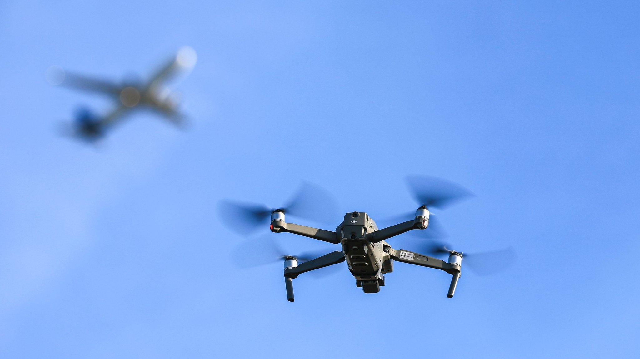 Drohne schwebt vor Flugzeug im Hintergrund
