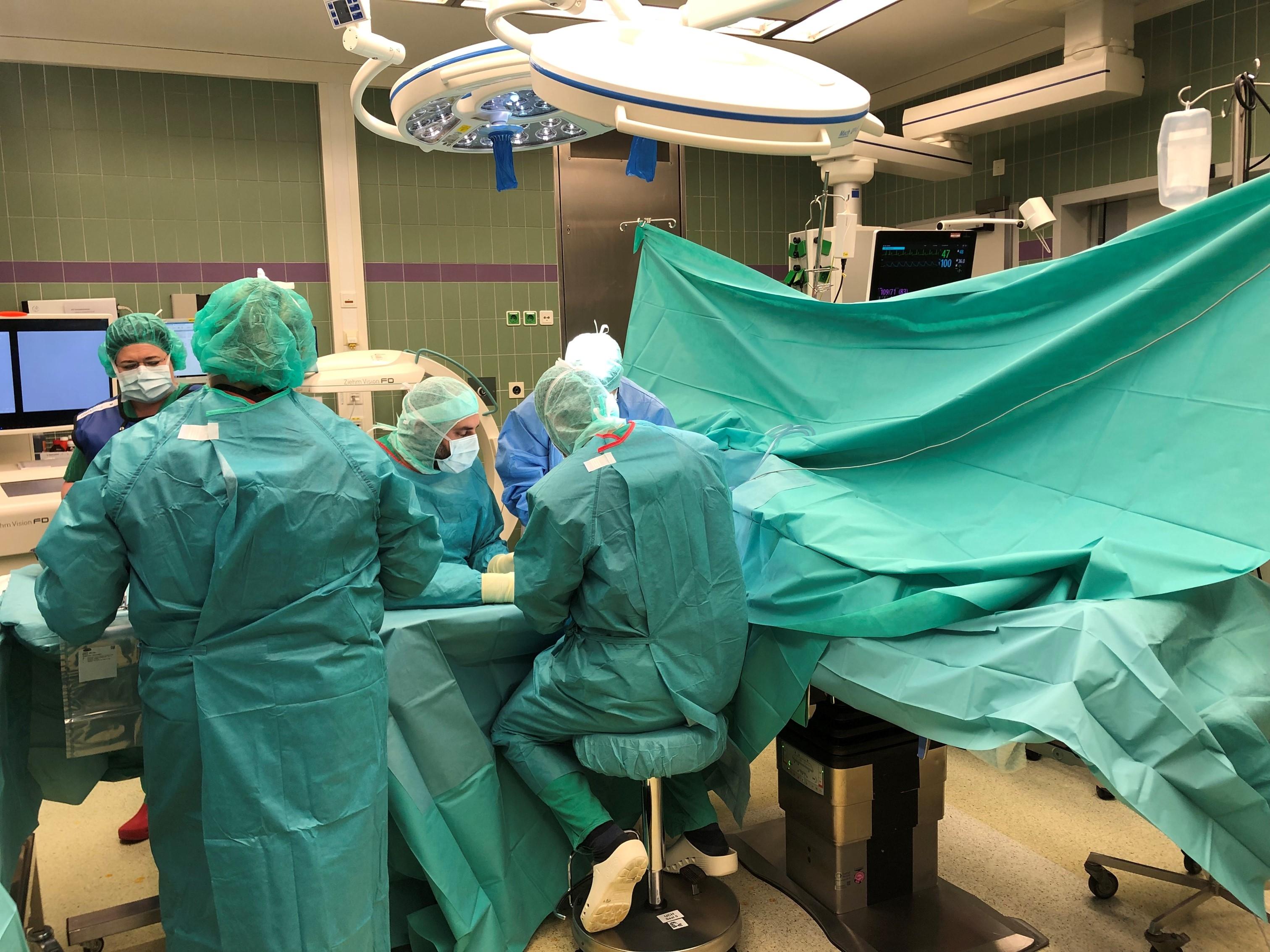 Ärzte und Pflegekräfte in grüner OP-Kleidung operieren einen Patienten.