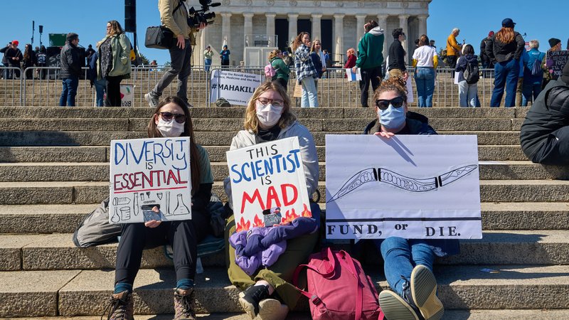 Drei Wissenschaftlerinnen protestieren bei einer Kundgebung mit Plakaten gegen die geplanten Kürzungen von Forschungsmitteln durch die US-amerikanische Regierung. | Bild: dpa-picture alliance / Middle East Images | Dominic Gwinn Drei Wissenschaftlerinnen protestieren bei einer Kundgebung mit Plakaten gegen die geplanten Kürzungen von Forschungsmitteln durch die US-amerikanische Regierung.
