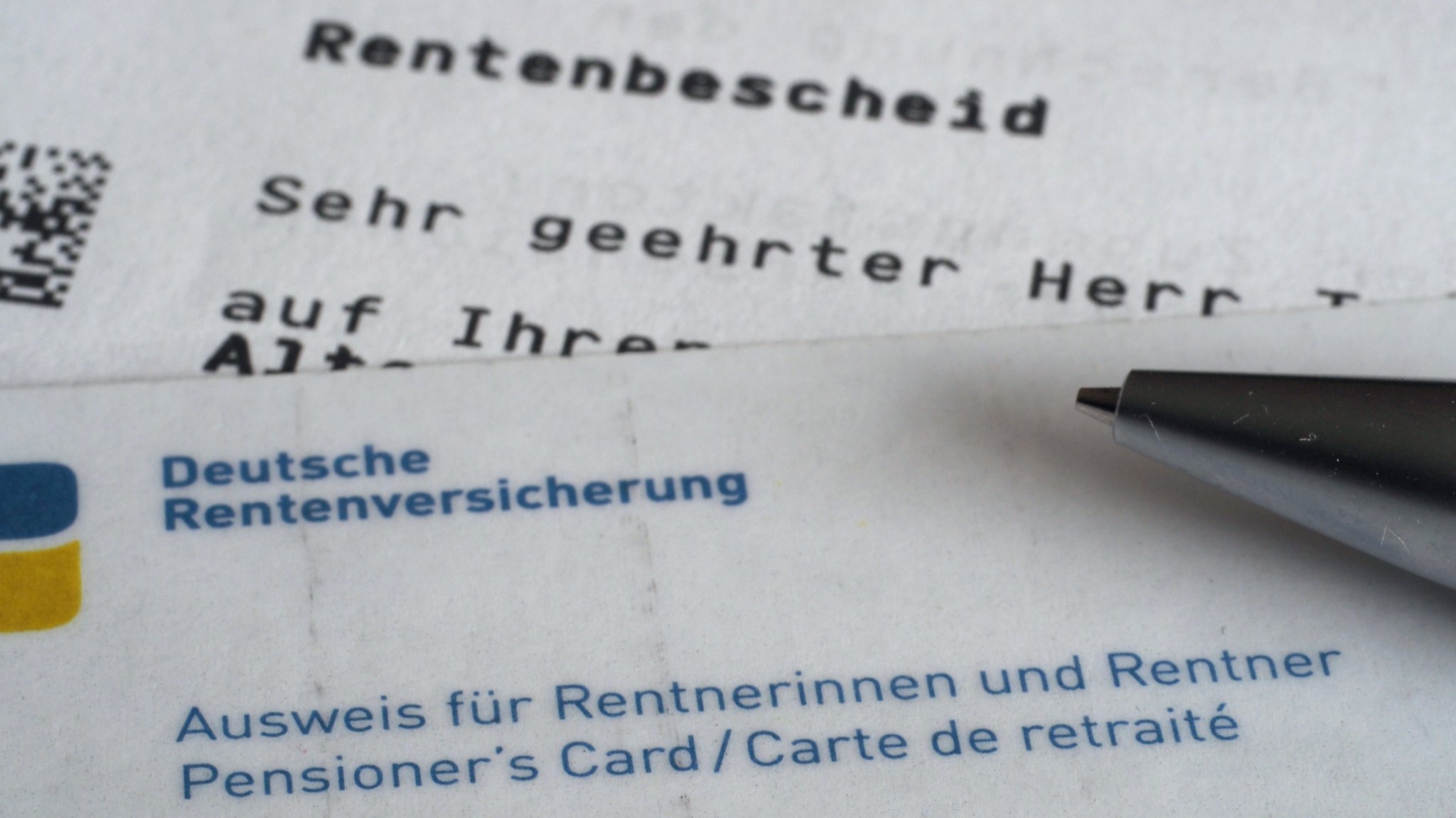 Ein Brief mit dem Betreff "Rentenbescheid" und ein Rentnerausweis liegen auf einem Tisch (Symbolbild).