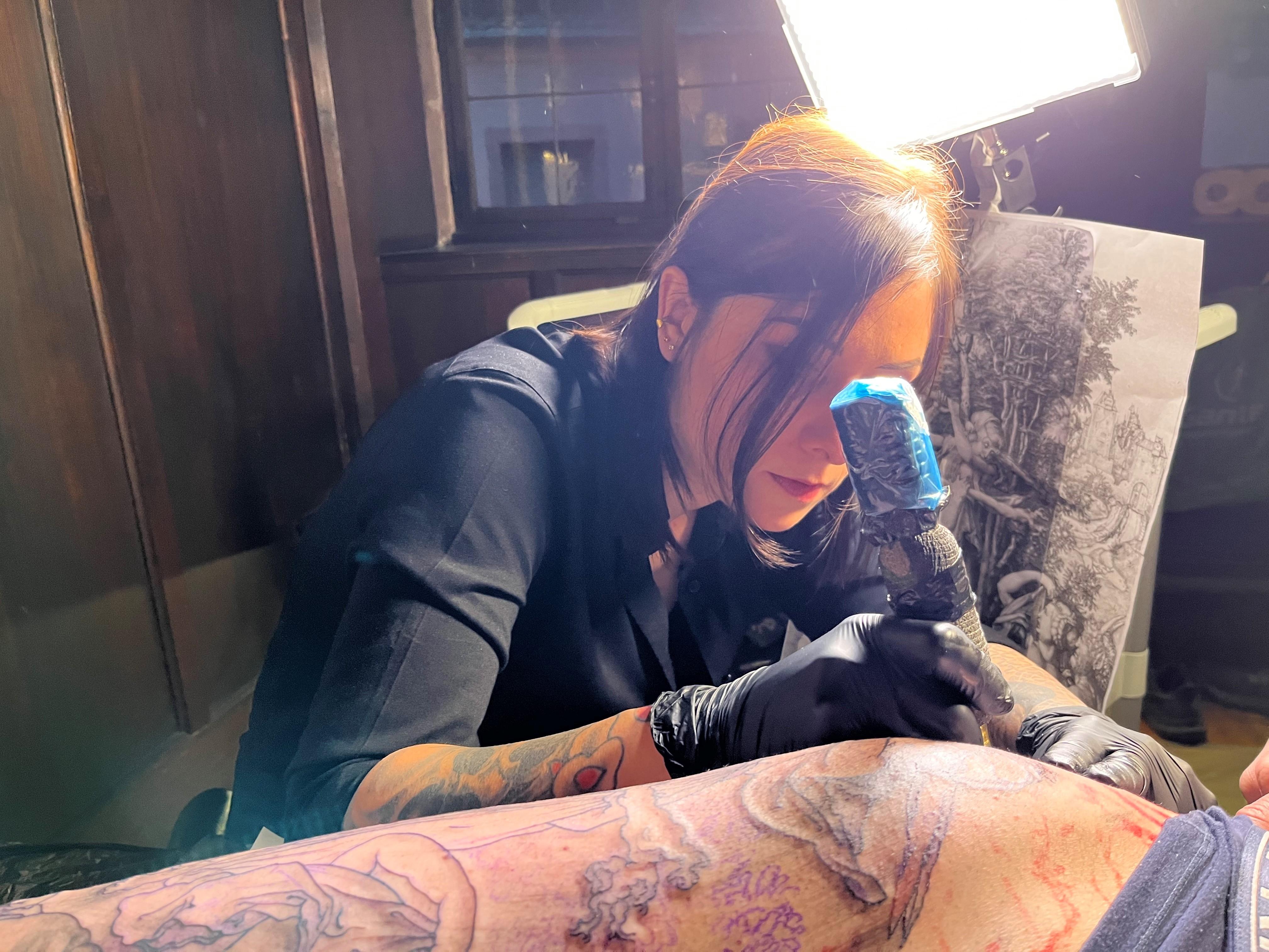 Eine Frau mit einer Tätowiernadel in der Hand.