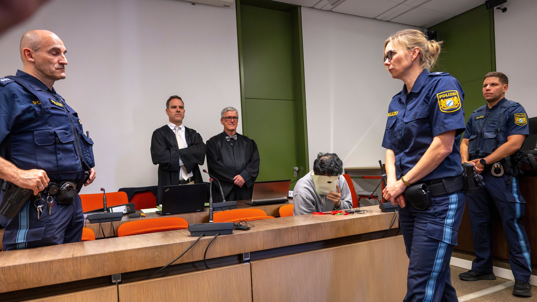 Der Angeklagte verdeckt beim Prozessauftakt sein Gesicht.