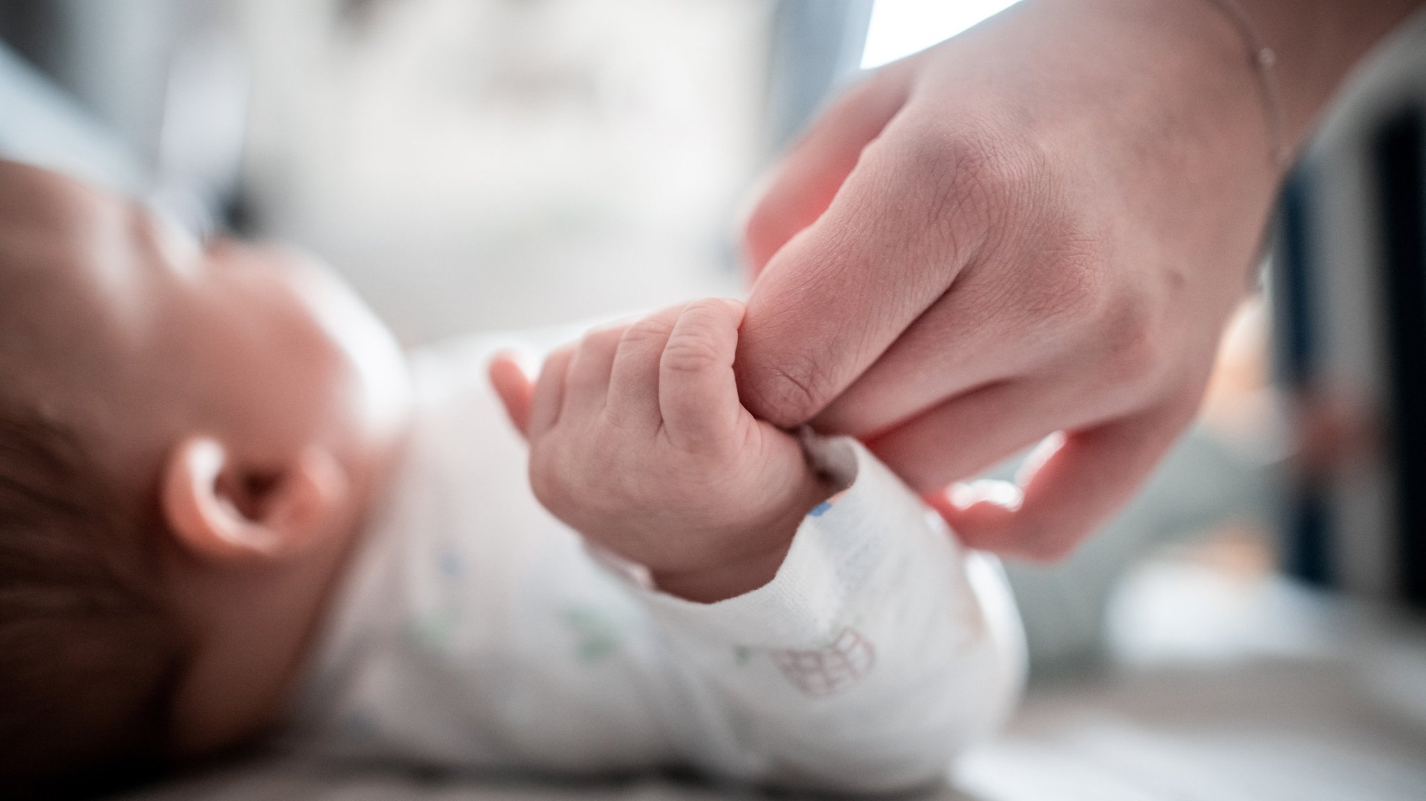Baby klammert sich an die Hand seiner Mutter.