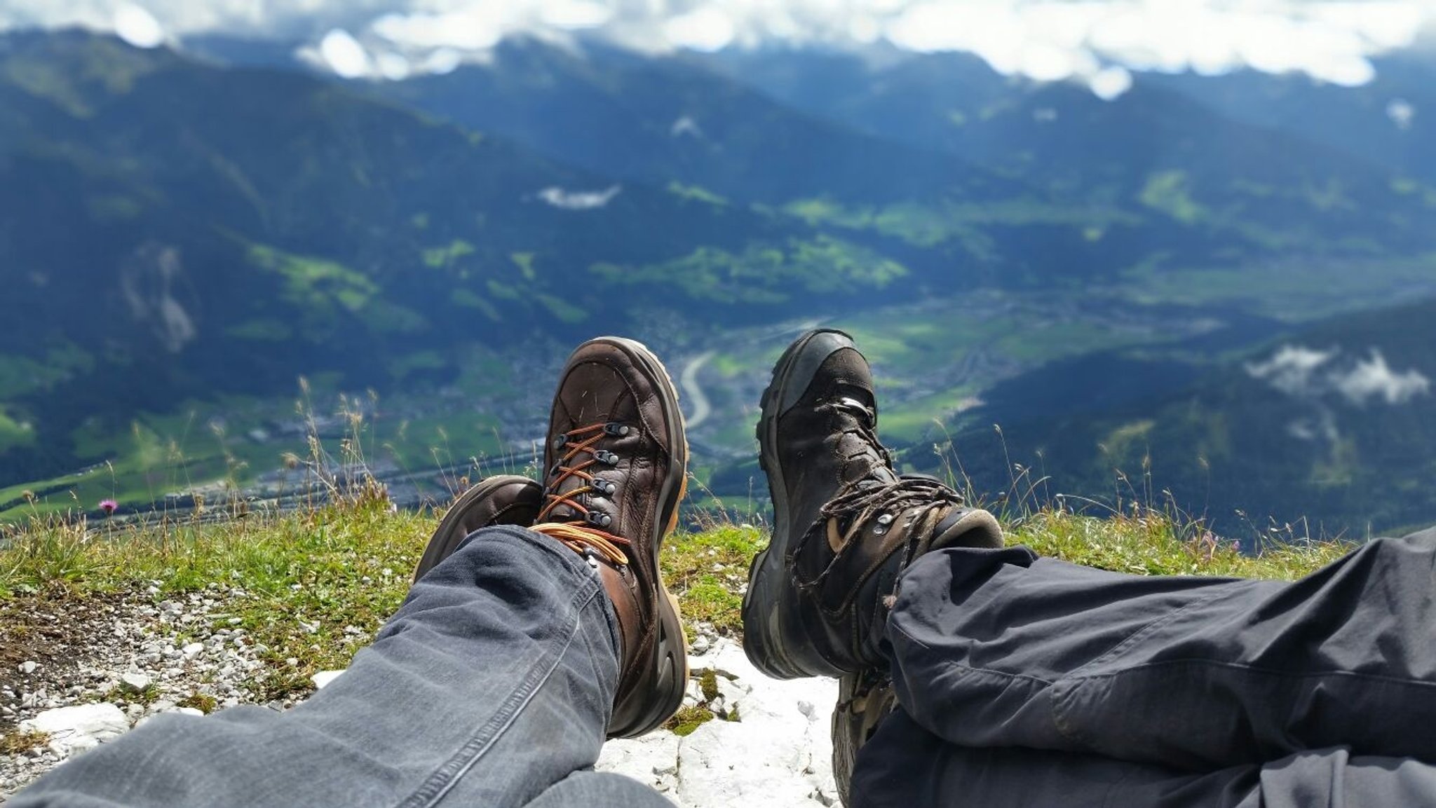 Zwei Paar Bergstiefel vor einer Bergkulisse.