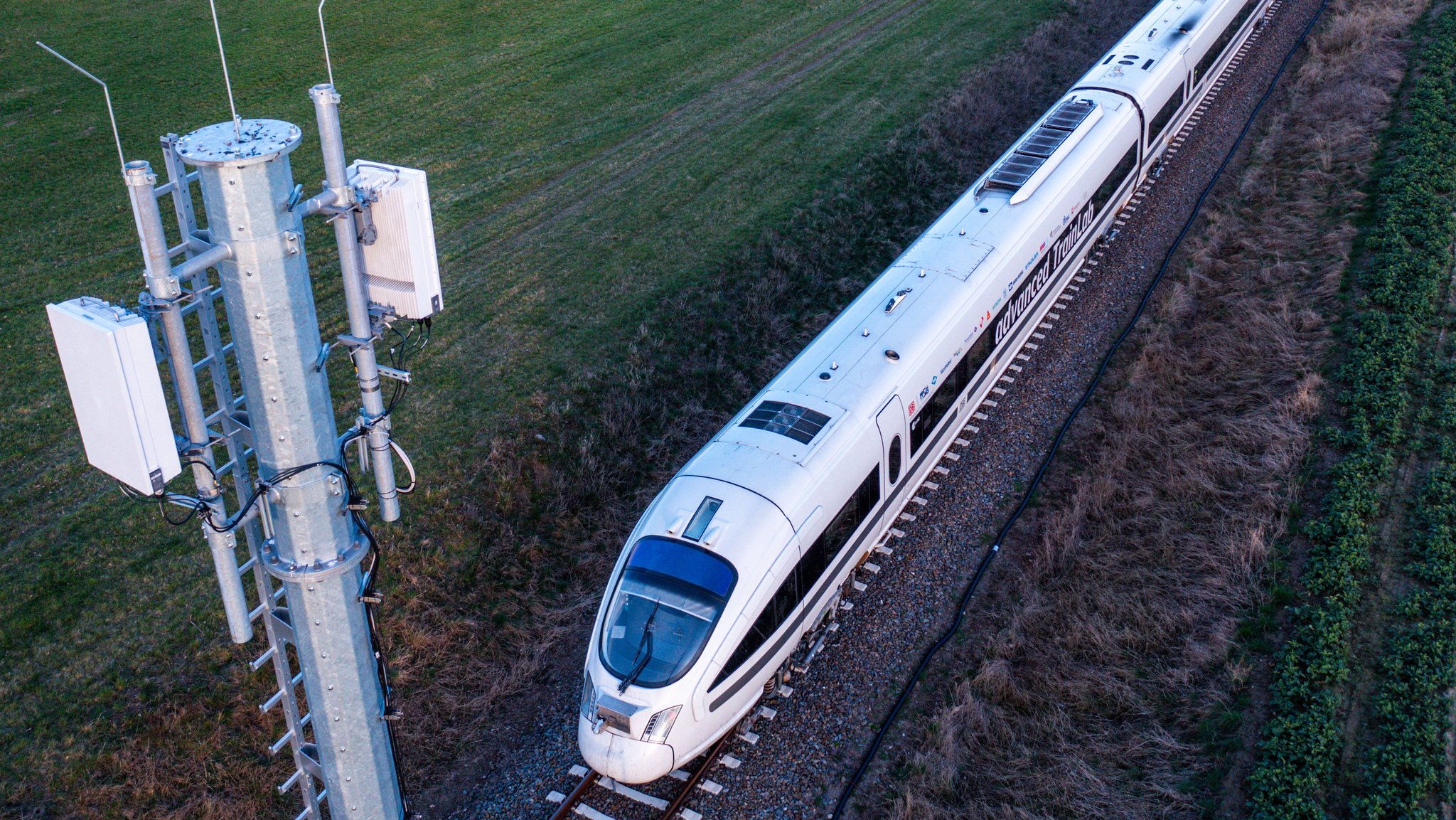 Symbolbild: Der Testzug "advanced TrainLab" der Deutschen Bahn fährt an einer der Antennenmasten für das 5G-Bahnprojekt vorbei.