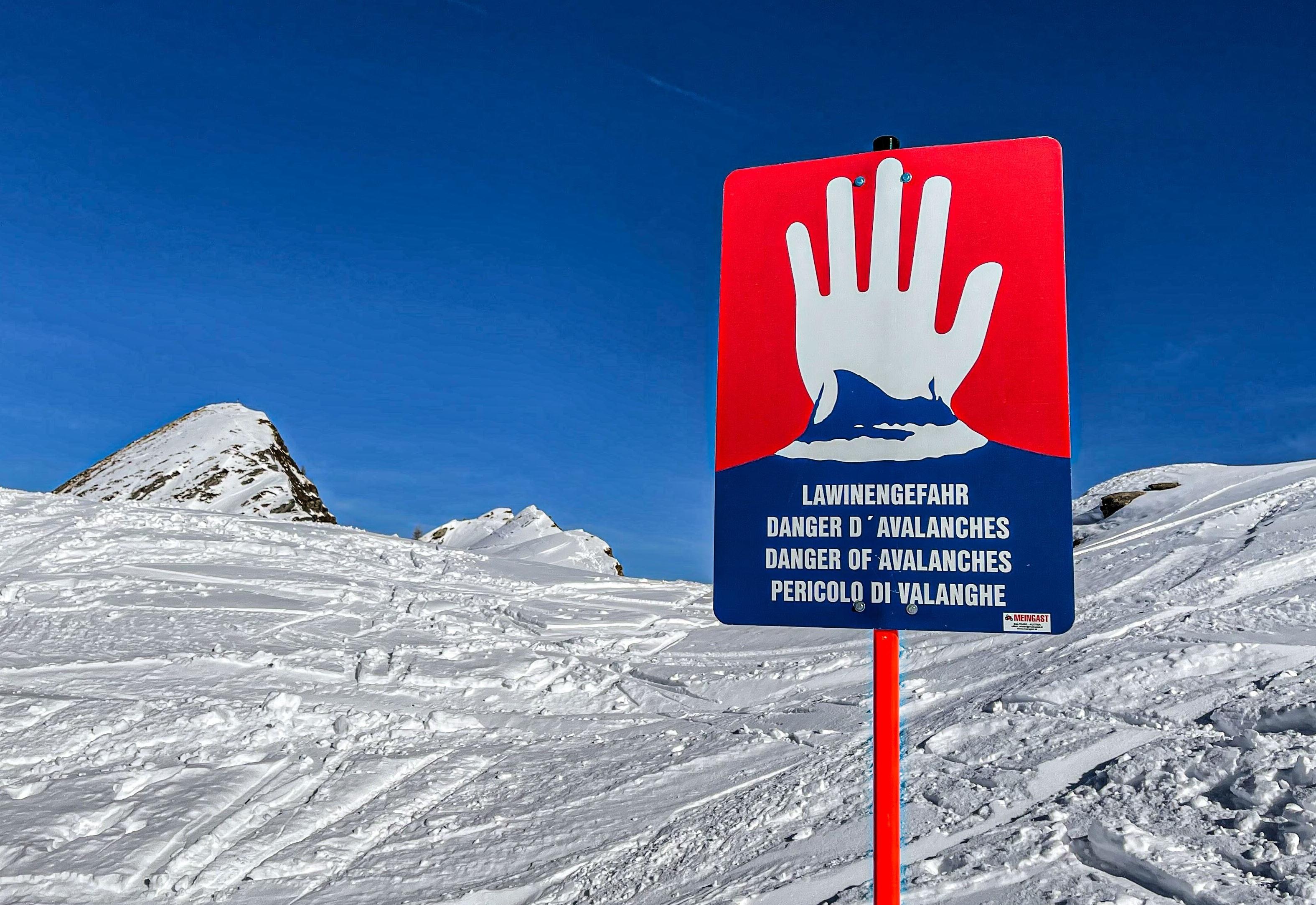 Schild Lawinengefahr vor Bergschneekulisse