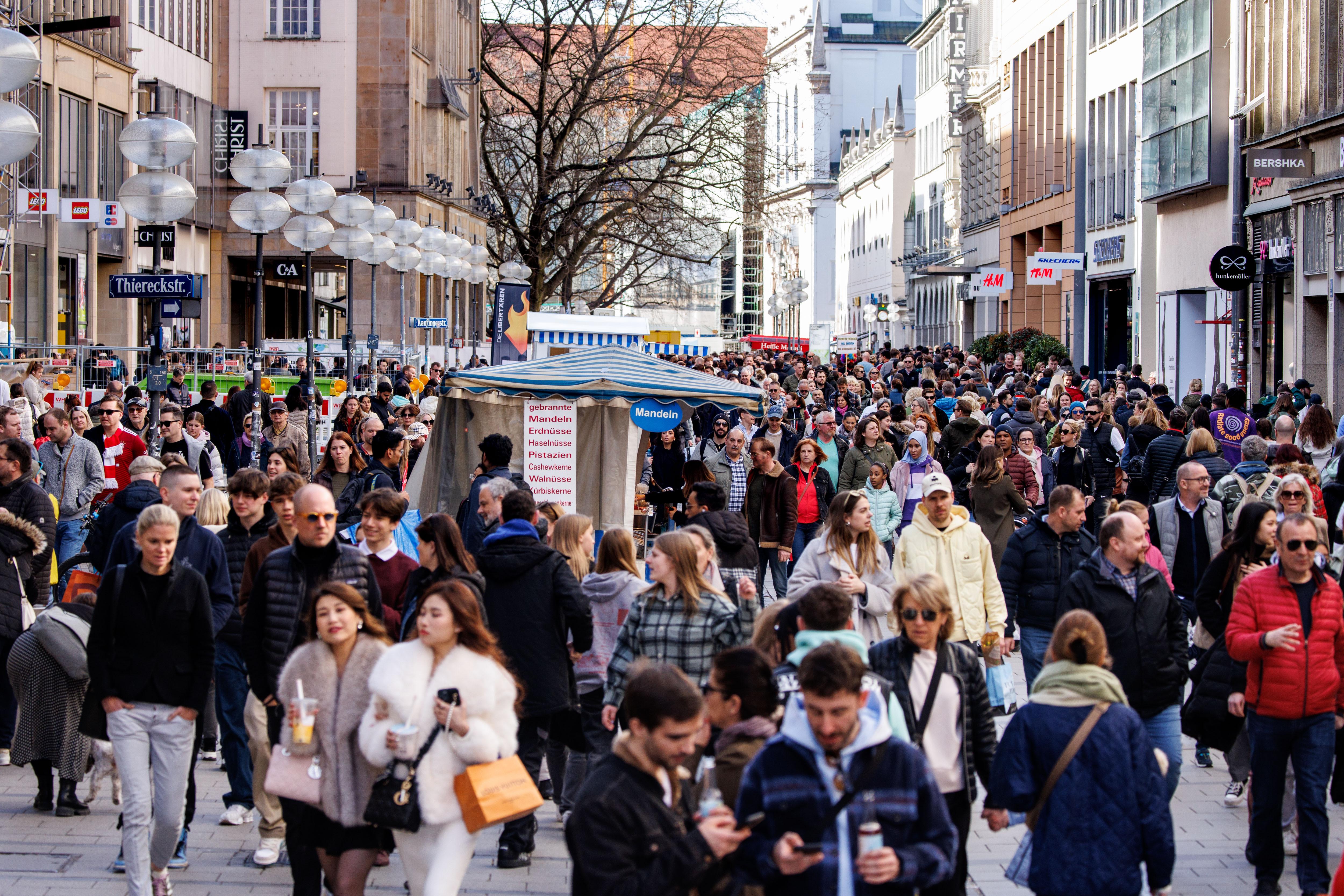 Zahlreiche Menschen gehen in der Innenstadt von München an Geschäften an der Kaufingerstraße vorüber.