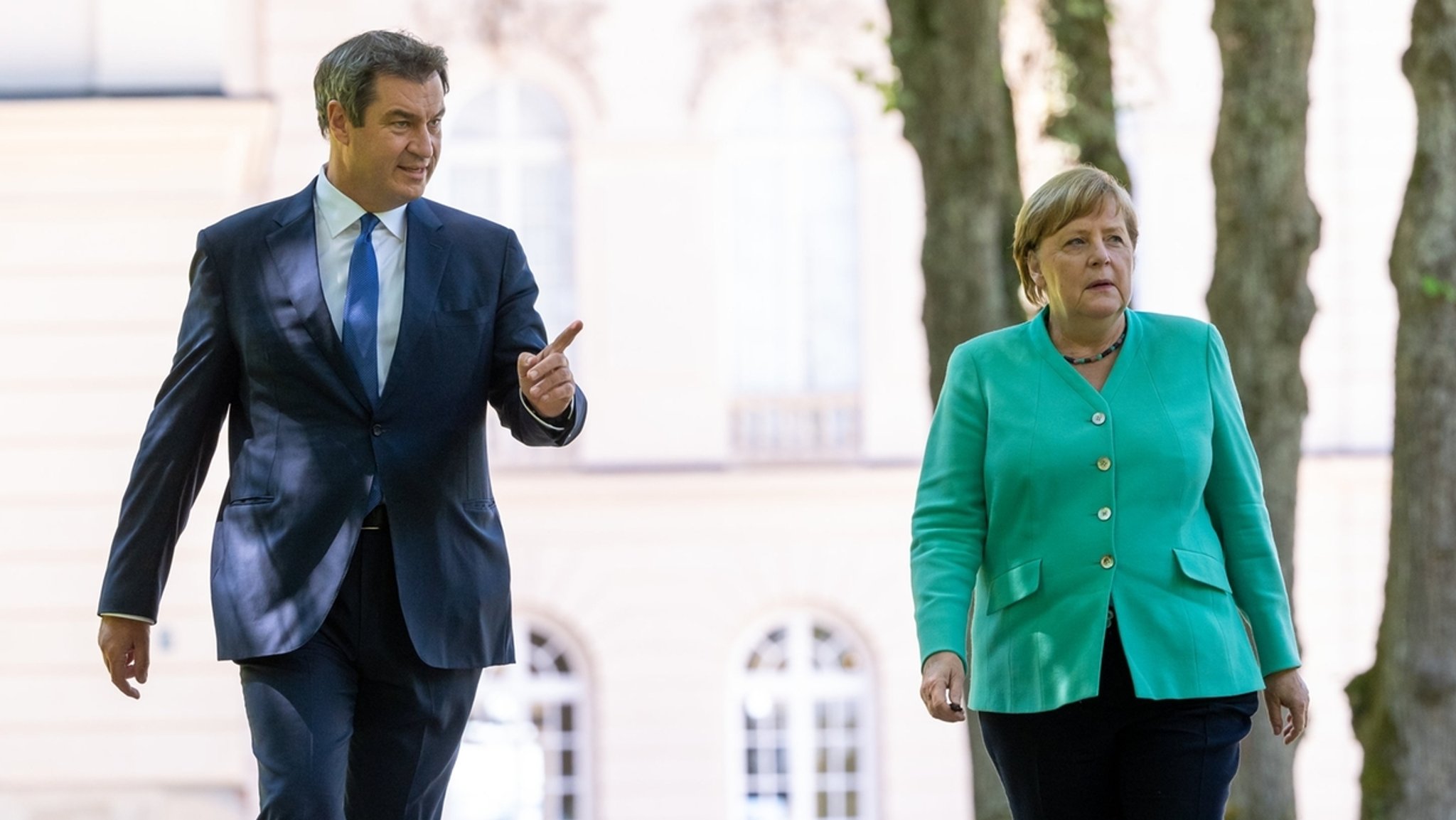 14.07.2020, Bayern, Herrenchiemsee: Markus Söder (CSU), Ministerpräsident von Bayern, und Bundeskanzlerin Angela Merkel (CDU) gehen nach der Sitzung des bayerischen Kabinetts im Neuen Schloss auf der Insel Herrenchiemsee gemeinsam zu einer abschließenden Pressekonferenz. 