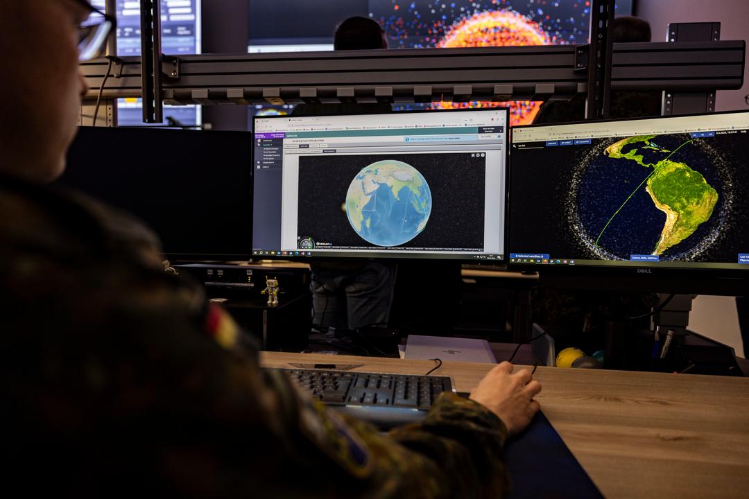Ein Soldat der Bundeswehr sitzt im Weltraumlagezentrum der Bundeswehr vor mehreren Monitoren 