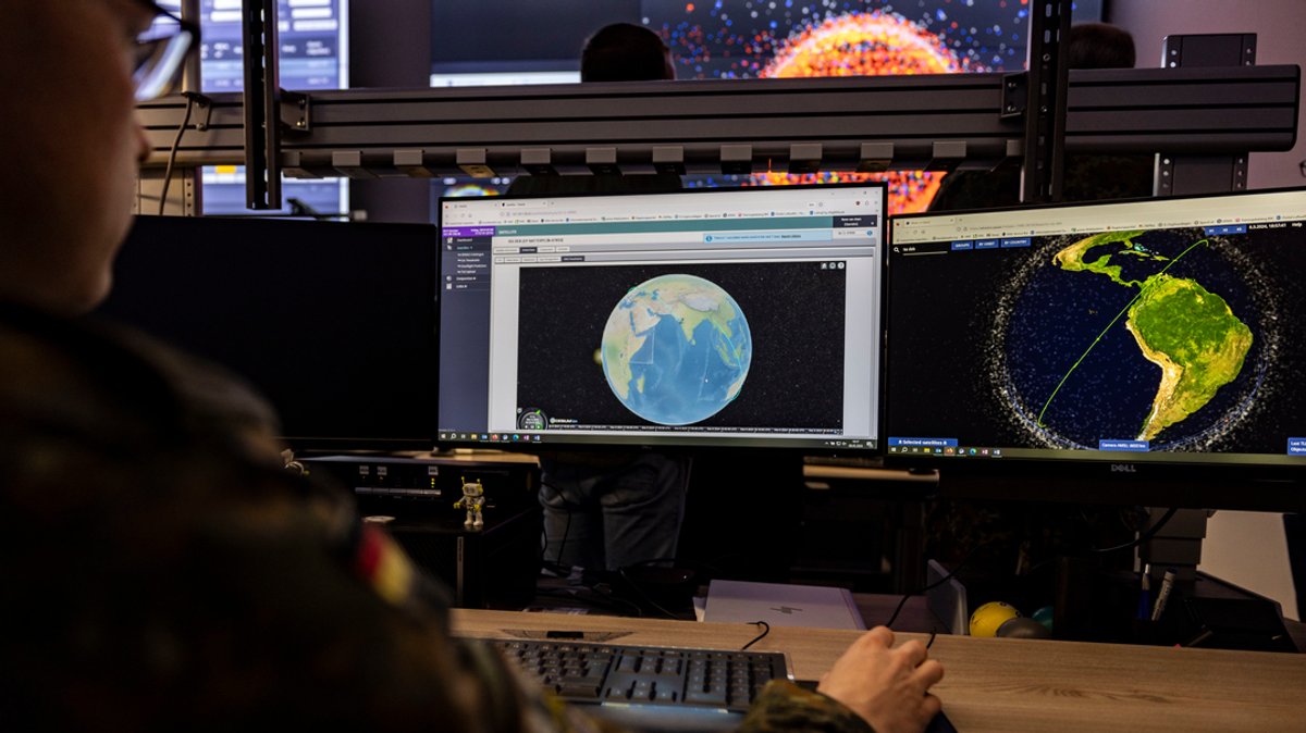 Ein Soldat der Bundeswehr sitzt im Weltraumlagezentrum der Bundeswehr vor mehreren Monitoren 