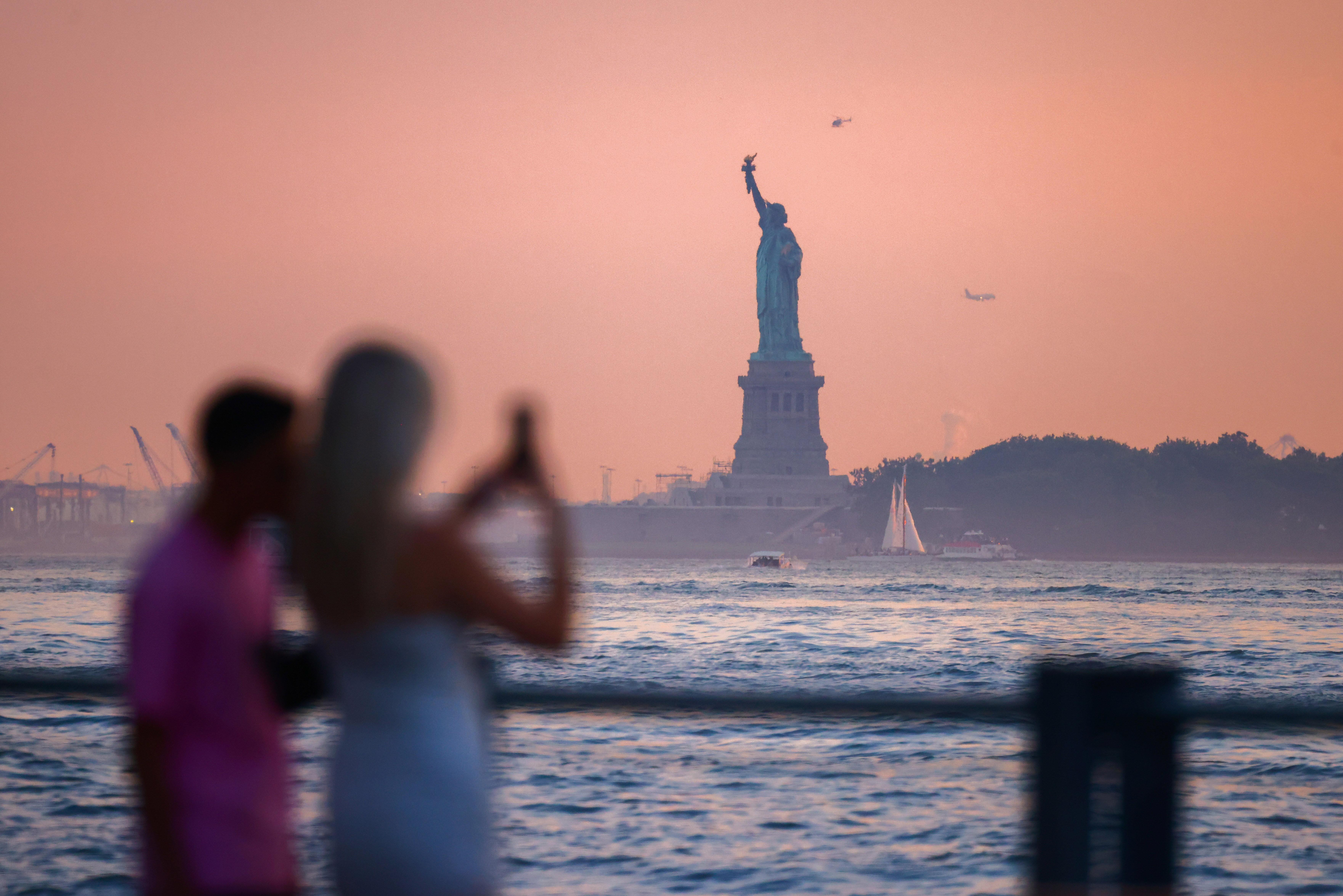 Touristen fotografieren die Freiheitsstatue in den USA in der Dämmerung