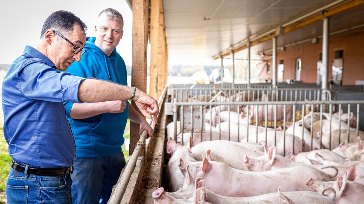 Cem Özdemir (l, Bündnis 90/Die Grünen), Bundesminister für Ernährung und Landwirtschaft, spricht bei seinem Besuch eines Schweinehaltungsbetriebes mit einem Landwirt.
