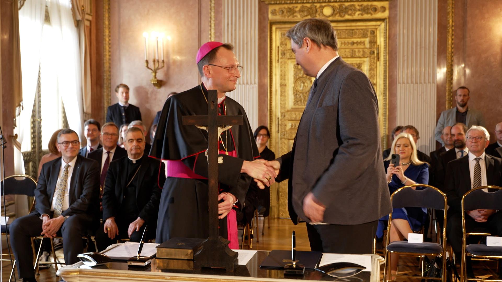 Erzbischof und Ministerpräsident schütteln sich die Hände. 