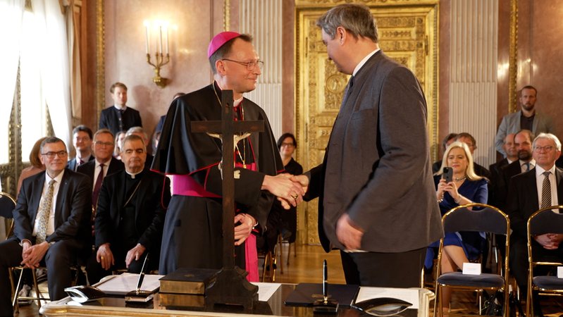 Erzbischof und Ministerpräsident schütteln sich die Hände. 