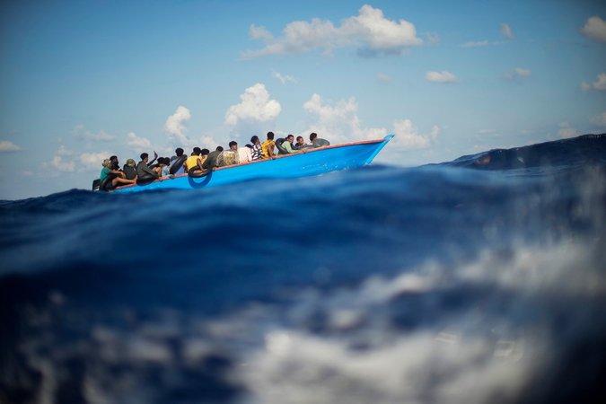 ARCHIV - 11.08.2022, Italien: Migranten sitzen in einem Holzboot südlich der italienischen Insel Lampedusa auf dem Mittelmeer.